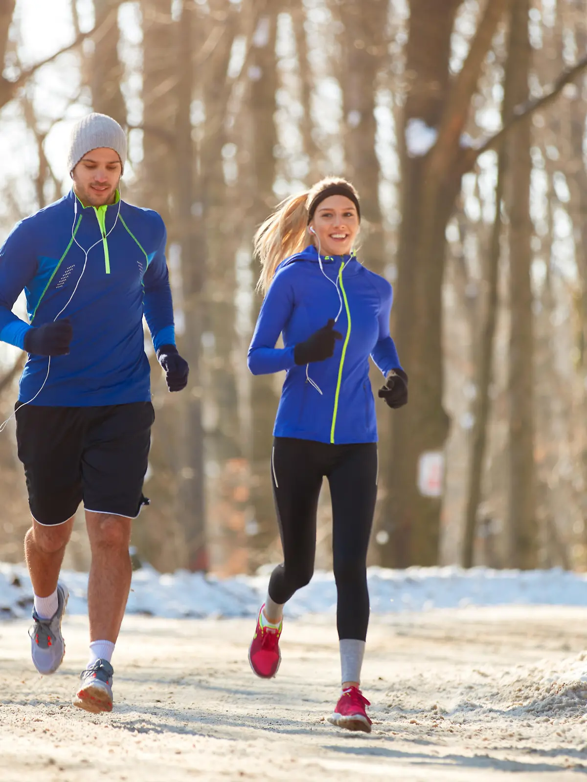 Young couple in the winter running together in nature