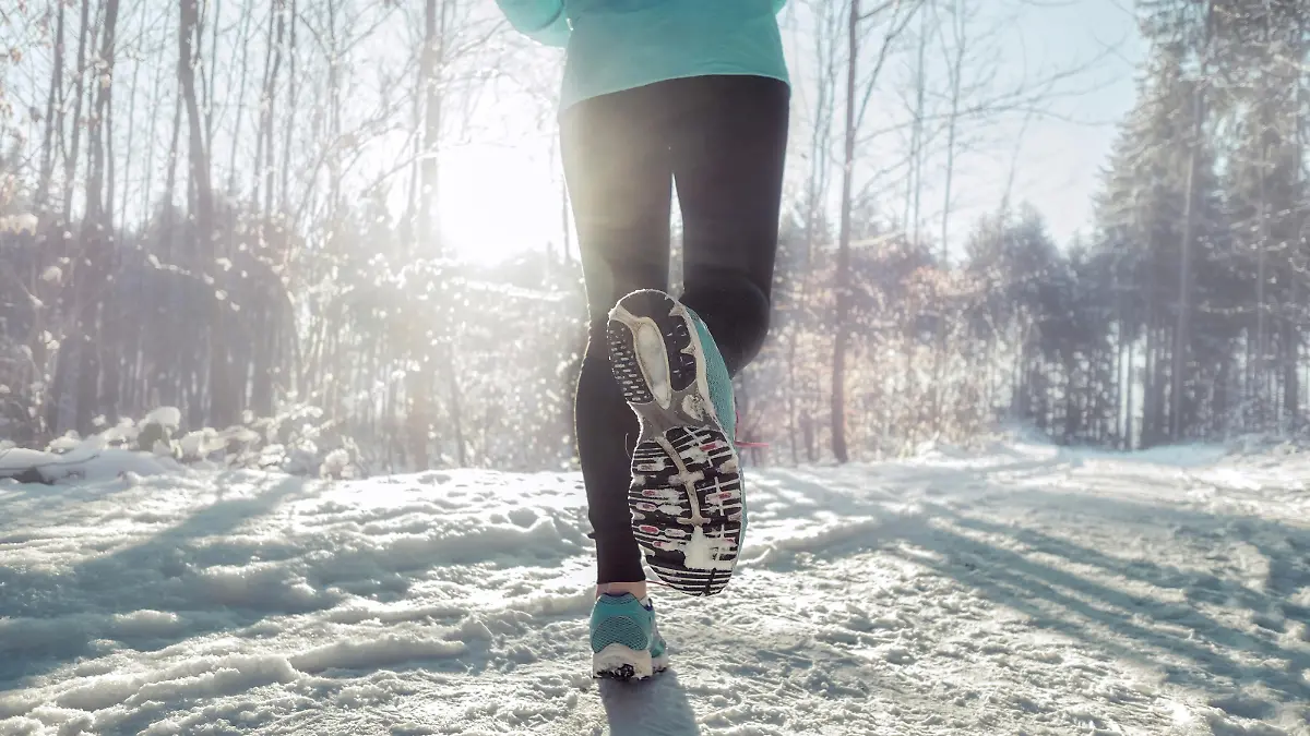 Woman Running at snowly winter under sunlight.