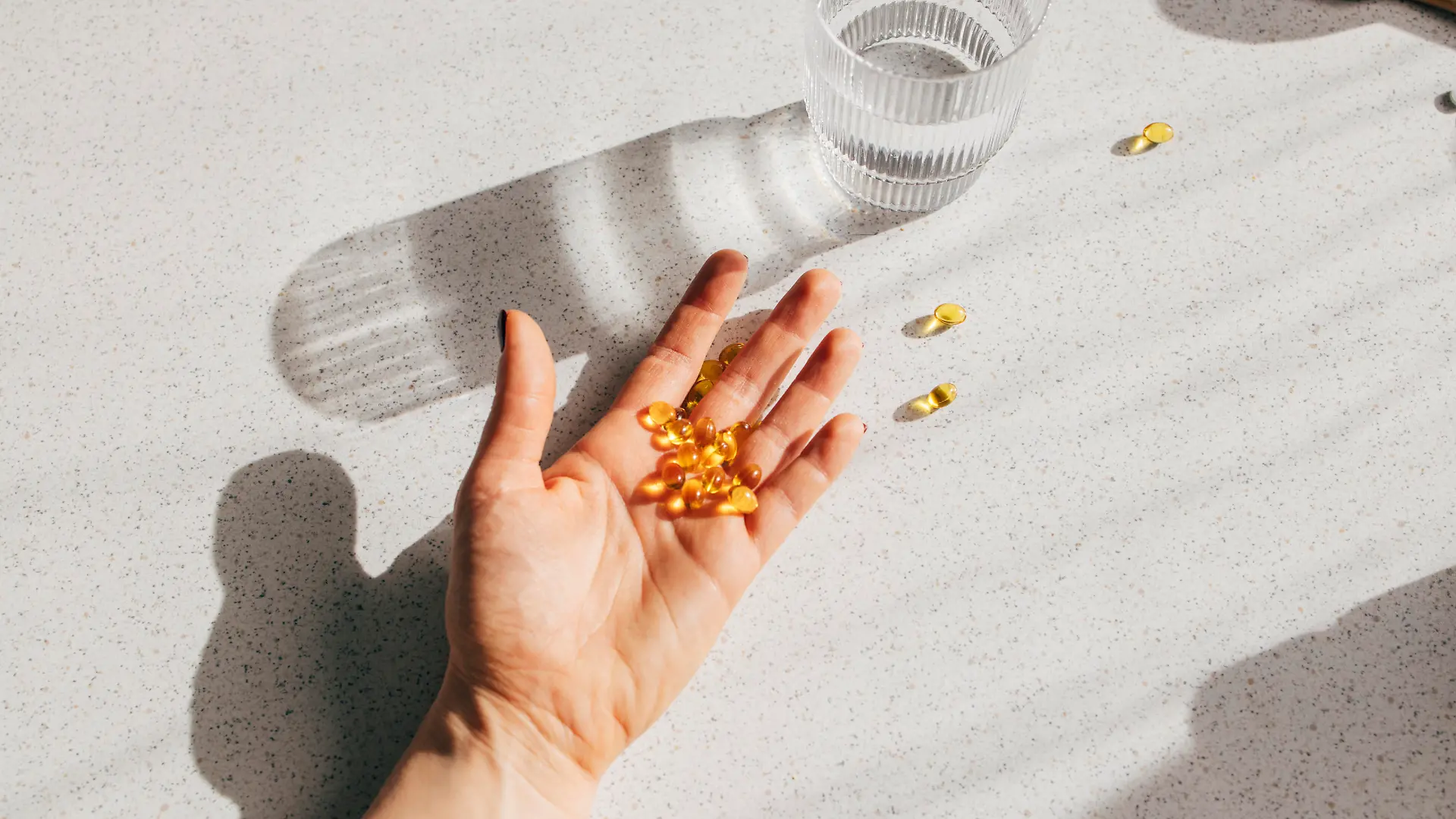 A high angle shot of an unrecognizable person's hand holding a bunch of vitamin D pills.