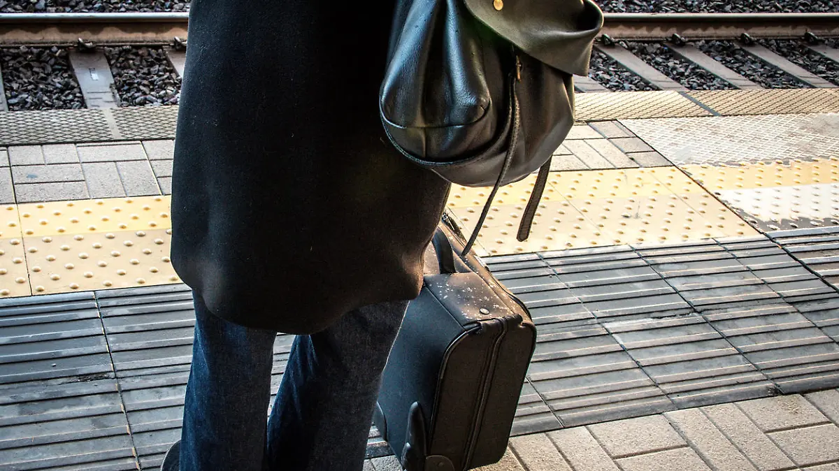 Woman waiting for a train with luggage.