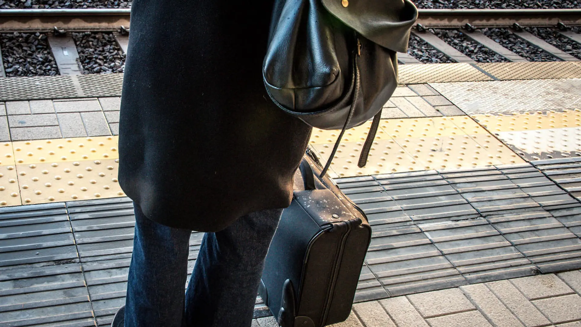 Woman waiting for a train with luggage.