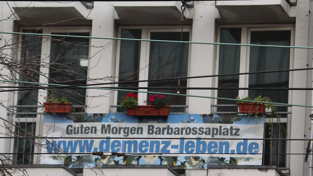 Auf einem Balkon ist ien Plakat mit der Aufschrift "Guten Morgen Barbarossaplatz www.demenz-leben.de"