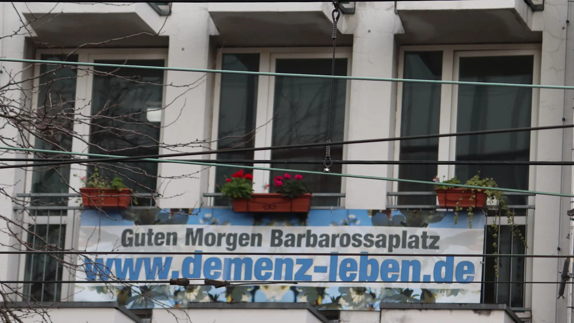 Auf einem Balkon ist ien Plakat mit der Aufschrift "Guten Morgen Barbarossaplatz www.demenz-leben.de"