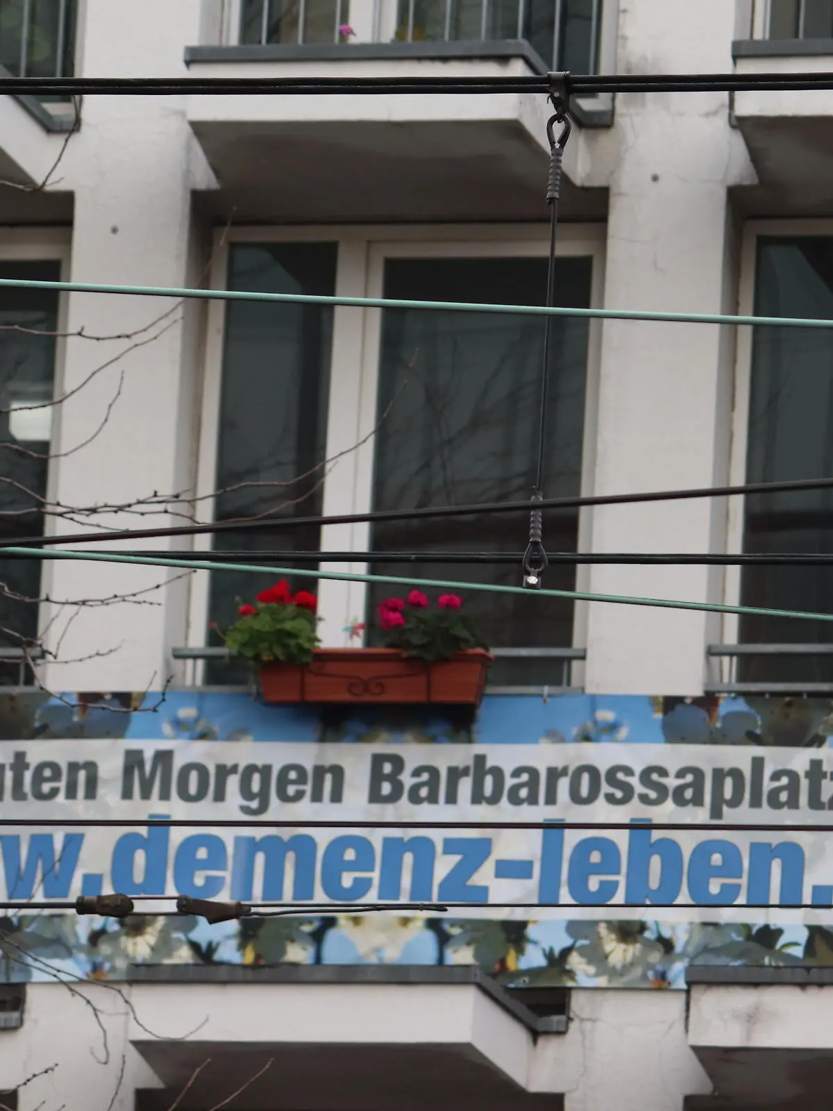 Auf einem Balkon ist ien Plakat mit der Aufschrift "Guten Morgen Barbarossaplatz www.demenz-leben.de"