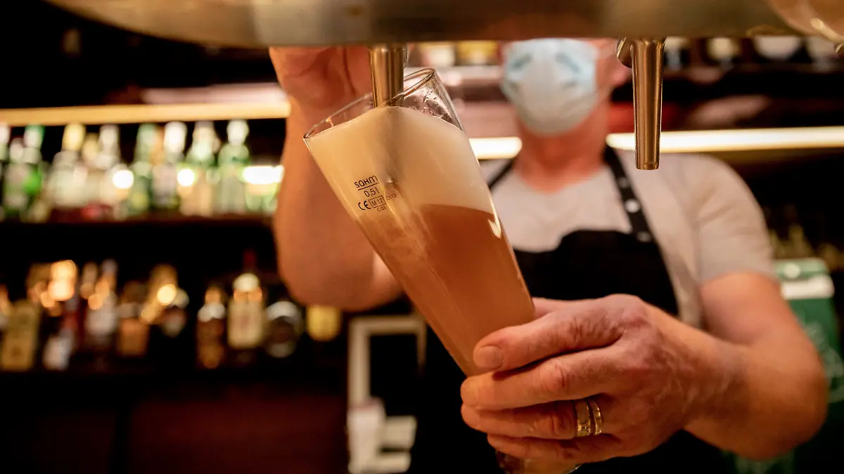 ARCHIV - 05.10.2020, Berlin: Ein Wirt mit Maske zapft in einer Kneipe Bier. Bei hohen Infektionszahlen dürfen Kommunen und Landkreise für die Gastronomie Sperrstunden verhängen. Aber nur wenige Landkreise machen bislang davon Gebrauch. Foto: Christoph Soeder/dpa +++ dpa-Bildfunk +++