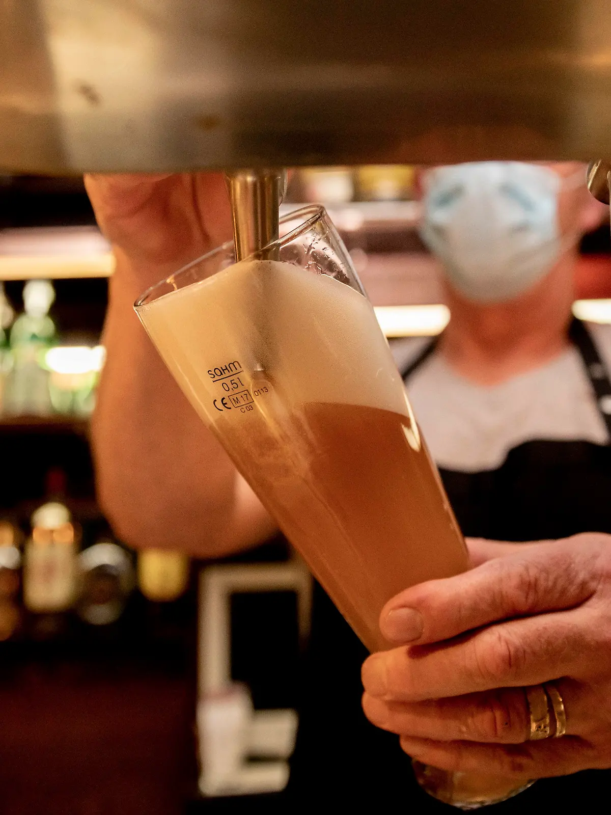 ARCHIV - 05.10.2020, Berlin: Ein Wirt mit Maske zapft in einer Kneipe Bier. Bei hohen Infektionszahlen dürfen Kommunen und Landkreise für die Gastronomie Sperrstunden verhängen. Aber nur wenige Landkreise machen bislang davon Gebrauch. Foto: Christoph Soeder/dpa +++ dpa-Bildfunk +++