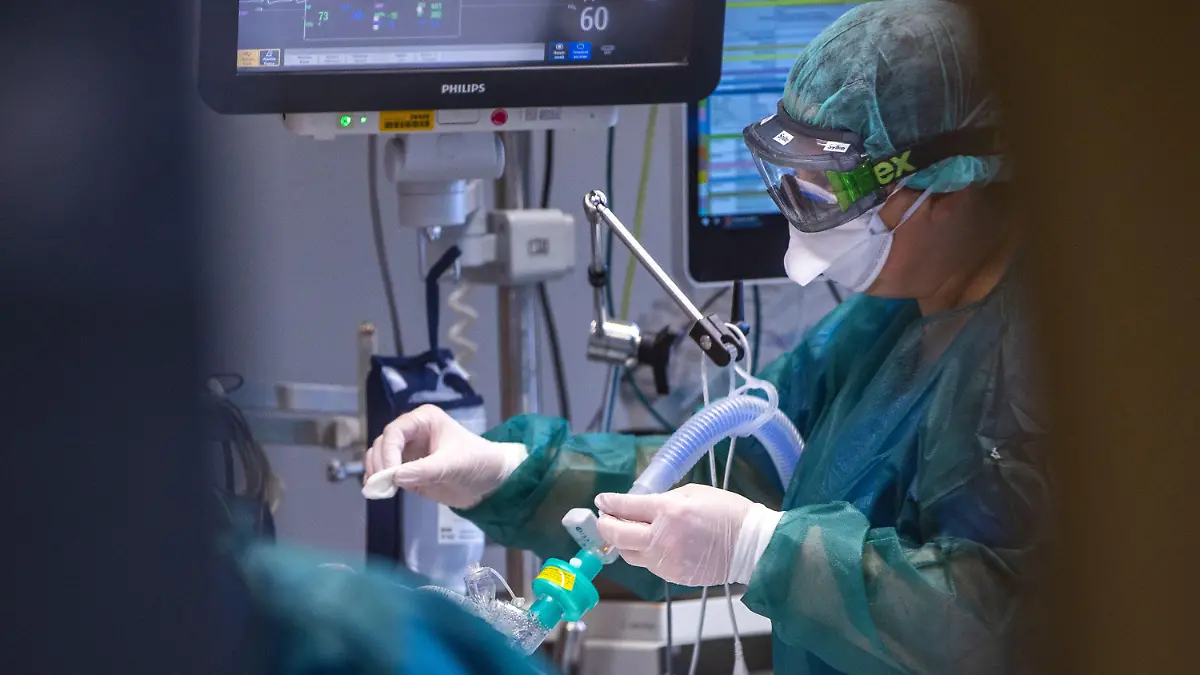 30.11.2021, Mecklenburg-Vorpommern, Rostock: Eine Intensivschwester betreut einen Patienten in einem der Behandlungszimmer der Intensivstation in der Universitätsmedizin Rostock. Angesichts der sprunghaft zunehmenden Zahl von Corona-Infizierten und der hohen Auslastung der Intensivstationen hat die Universitätsmedizin einen Covid-Ethikbeirat gebildet. Auch Patienten aus Sachsen werden in der Klinik behandelt. Foto: Jens Büttner/dpa-Zentralbild/dpa +++ dpa-Bildfunk +++