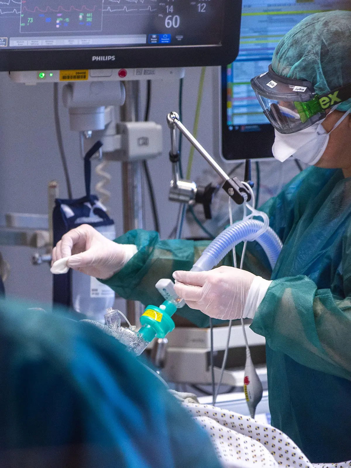 30.11.2021, Mecklenburg-Vorpommern, Rostock: Eine Intensivschwester betreut einen Patienten in einem der Behandlungszimmer der Intensivstation in der Universitätsmedizin Rostock. Angesichts der sprunghaft zunehmenden Zahl von Corona-Infizierten und der hohen Auslastung der Intensivstationen hat die Universitätsmedizin einen Covid-Ethikbeirat gebildet. Auch Patienten aus Sachsen werden in der Klinik behandelt. Foto: Jens Büttner/dpa-Zentralbild/dpa +++ dpa-Bildfunk +++