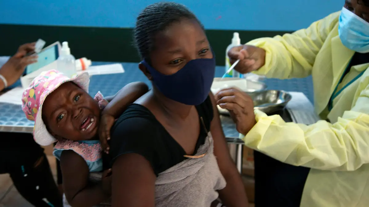 ARCHIV - 21.10.2021, Südafrika, Diepsloot: Ein Baby weint, als seine Mutter am 21.10.2021 im Township Diepsloot in der Nähe von Johannesburg eine Impfung mit dem Impfstoff von Pfizer/Biontech gegen Covid-19 erhält. Die Ausbreitung einer neuen möglicherweise sehr gefährlichen Variante des Coronavirus im südlichen Afrika hat international Besorgnis ausgelöst. Experten befürchten, dass die Variante B.1.1.529 wegen ungewöhnlich vieler Mutationen nicht nur hoch ansteckend sei, sondern auch den Schutzschild der Impfstoffe leichter durchdringen könnte. (Zu dpa «Neue Corona-Supervariante im Süden Afrikas») Foto: Denis Farrell/AP/dpa +++ dpa-Bildfunk +++