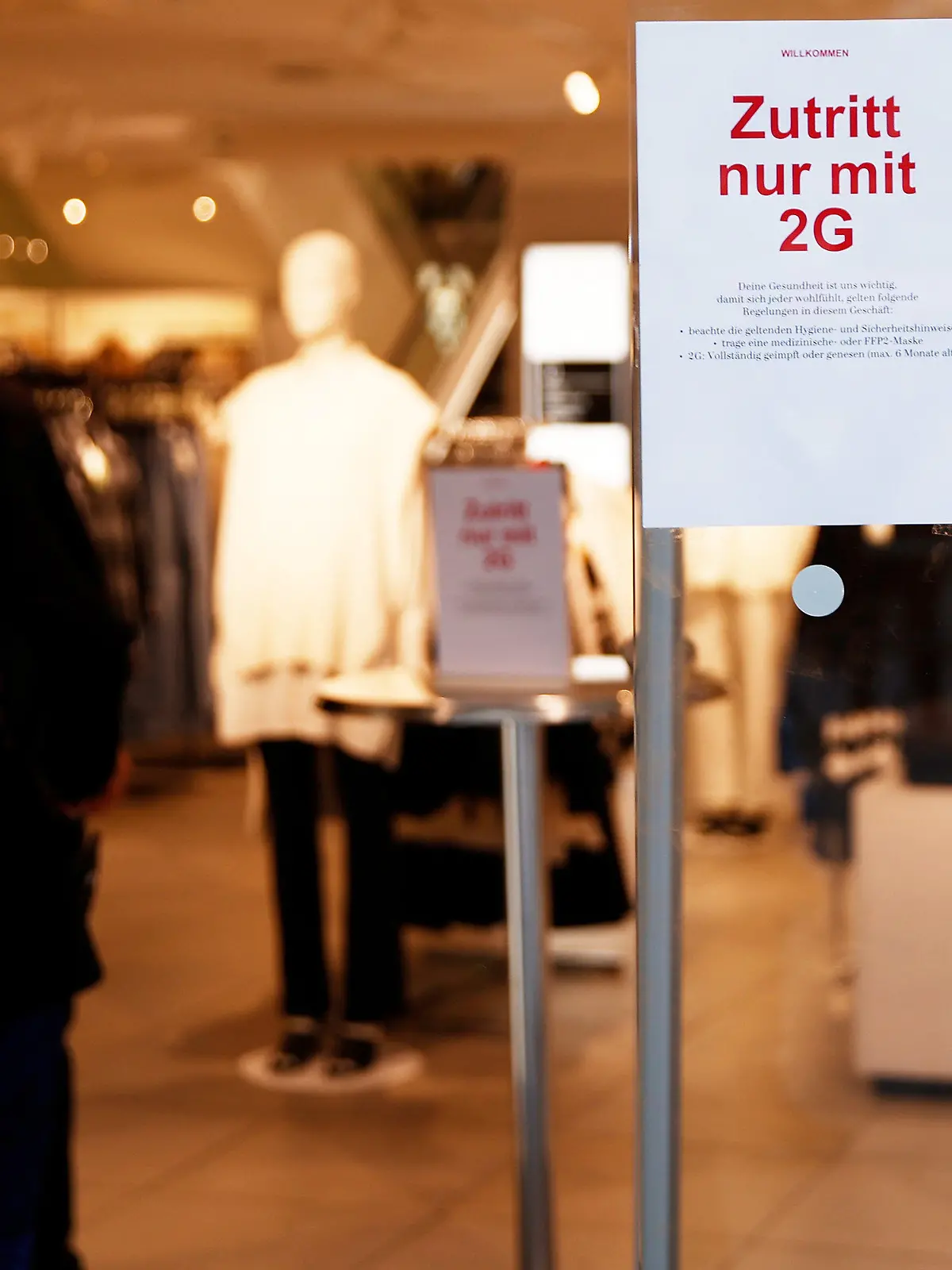 ARCHIV - 27.11.2021, Berlin: Ein Schild am Eingang eines Geschäftes weist auf die 2G-Regel hin. Der stationäre Handel sieht sich als Opfer einer unsinnigen «Show-Maßnahme» der Politik und fürchtet Umsatzrückgänge von bis zu 50 Prozent. Doch natürlich würde es bei 2G auch Gewinner geben.(zu dpa "Alarmstimmung im Handel: 2G-Regelung bedroht Weihnachtsgeschäft") Foto: Carsten Koall/dpa +++ dpa-Bildfunk +++