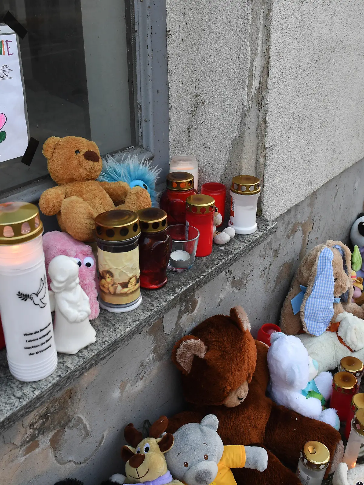 ARCHIV - 22.01.2019, Mecklenburg-Vorpommern, Torgelow: Kerzen und Plüschtiere stehen vor dem Eingang des Hauses, wo am 12.01.2019 die sechsjährige Leonie ums Leben kam. Vor zwei Jahren starb in Vorpommern die sechsjährige Leonie. Sie war vom Stiefvater schwer misshandelt worden. In einem Revisionsprozess wird dessen Motiv nochmal genauer geprüft. Dazu soll die Mutter als Zeugin gehört werden. (zu dpa: "Mordfall Leonie: Revisionsprozesses geht weiter, Mutter als Zeugin") Foto: Stefan Sauer/dpa +++ dpa-Bildfunk +++