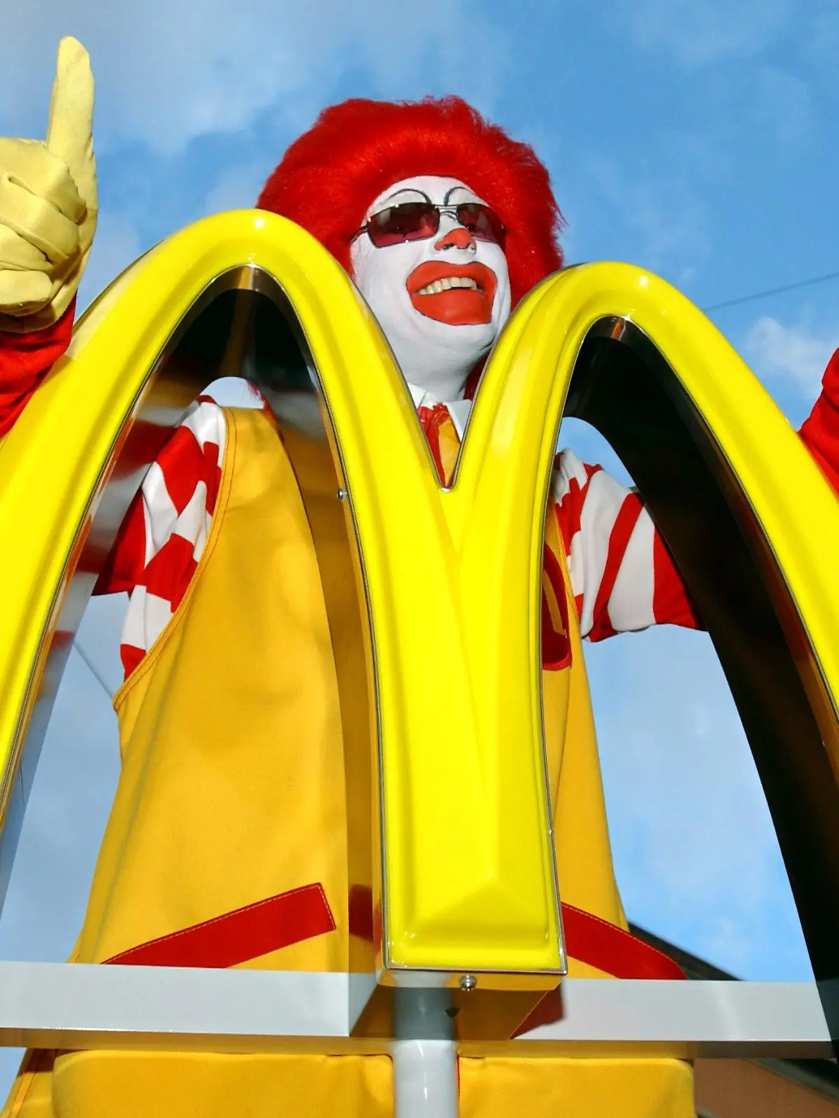 ARCHIV - 02.09.2003, Bayern, München: «Ronald McDonald» steht während einer Pressekonferenz hinter dem neu gestalteten Logo von «McDonald's». Das goldene M der Burgerkette McDonald's ist ein weltweit bekanntes Emblem für Fast Food. Vor 50 Jahren eröffnete die erste Filiale in Deutschland. Foto: Peter Kneffel/dpa +++ dpa-Bildfunk +++