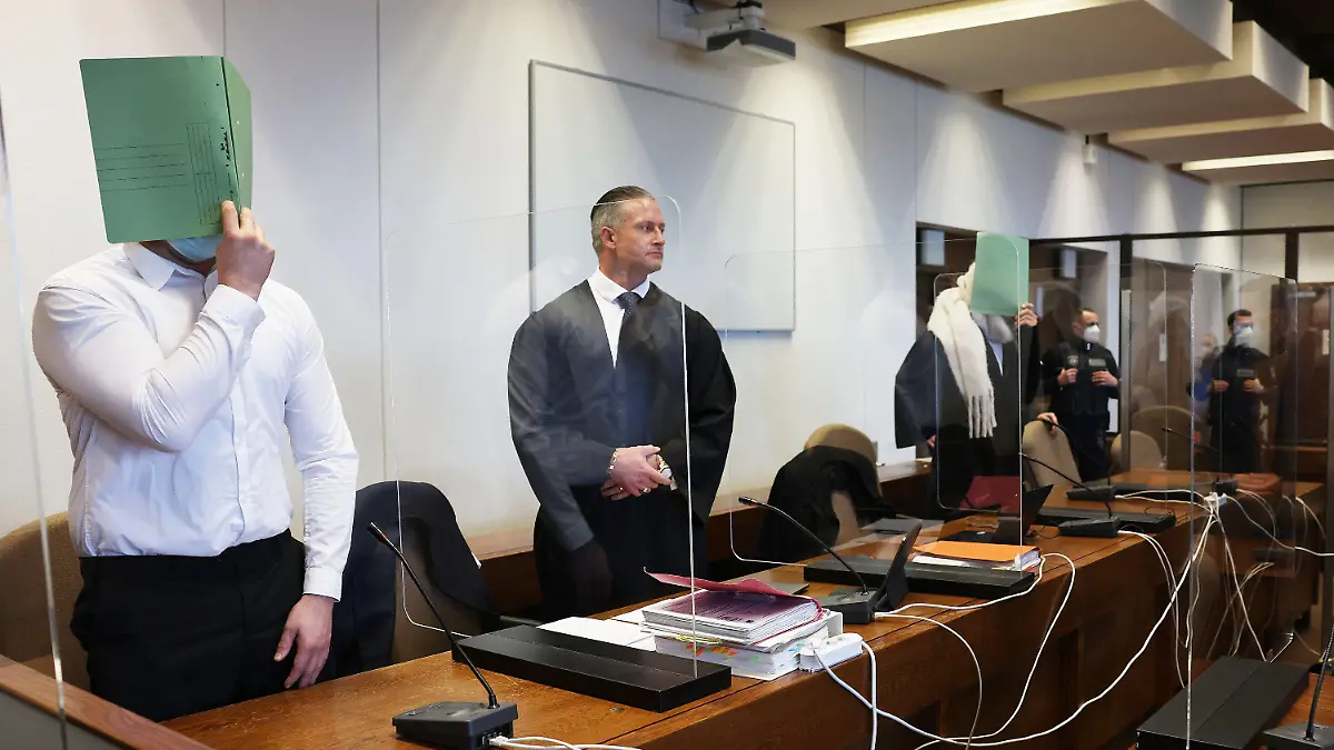 02.12.2021, Nordrhein-Westfalen, Köln: Zwei Angeklagte halten sich neben ihren Verteidigern im Gerichtssaal eine Mappe vor das Gesicht. Eine mutmaßliche Vergewaltigung an Karneval 2020 beschäftigt das Kölner Landgericht. Angeklagt sind drei Männer im Alter zwischen 31 und 42 Jahren. Foto: Oliver Berg/dpa +++ dpa-Bildfunk +++