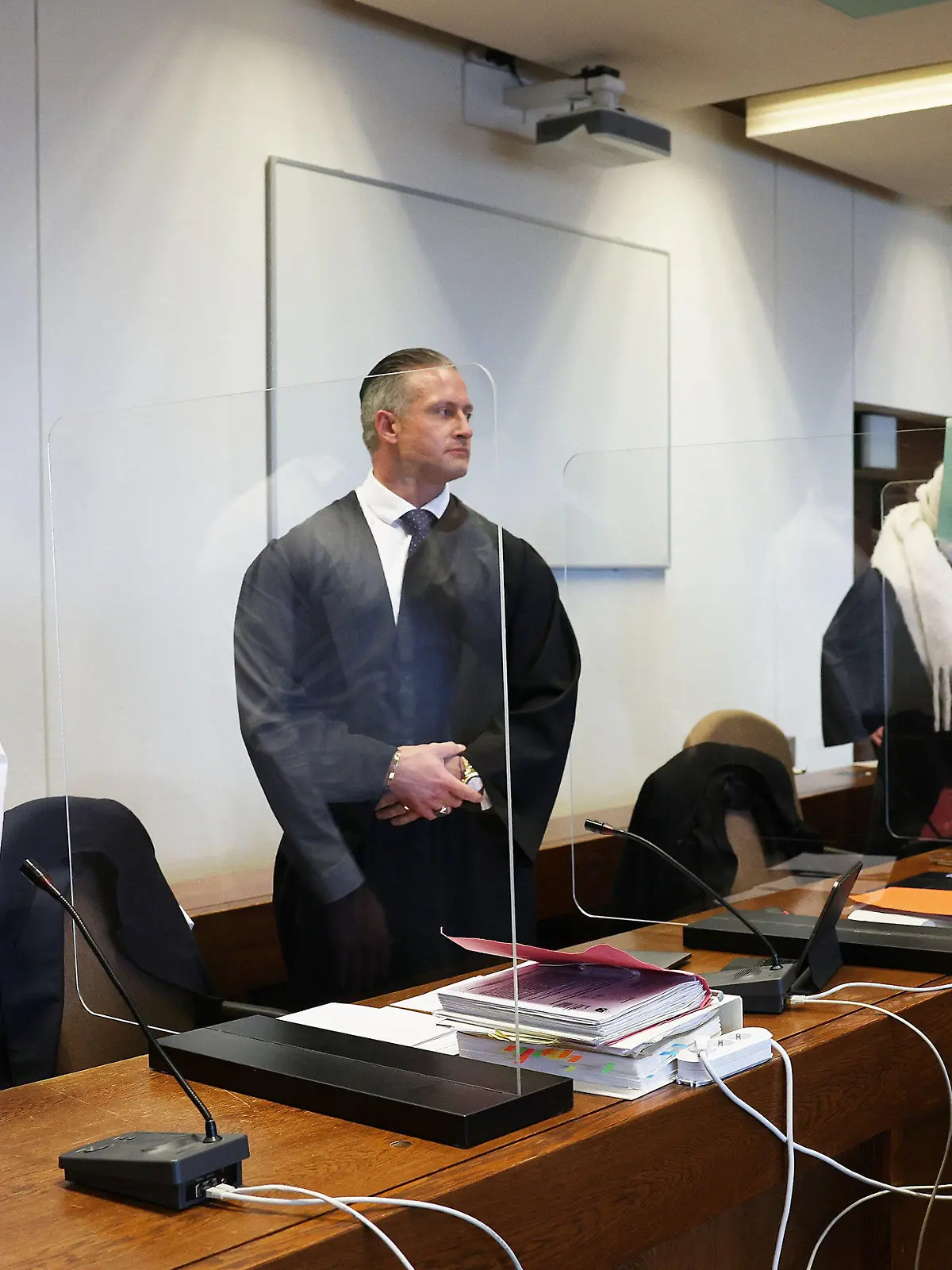 02.12.2021, Nordrhein-Westfalen, Köln: Zwei Angeklagte halten sich neben ihren Verteidigern im Gerichtssaal eine Mappe vor das Gesicht. Eine mutmaßliche Vergewaltigung an Karneval 2020 beschäftigt das Kölner Landgericht. Angeklagt sind drei Männer im Alter zwischen 31 und 42 Jahren. Foto: Oliver Berg/dpa +++ dpa-Bildfunk +++