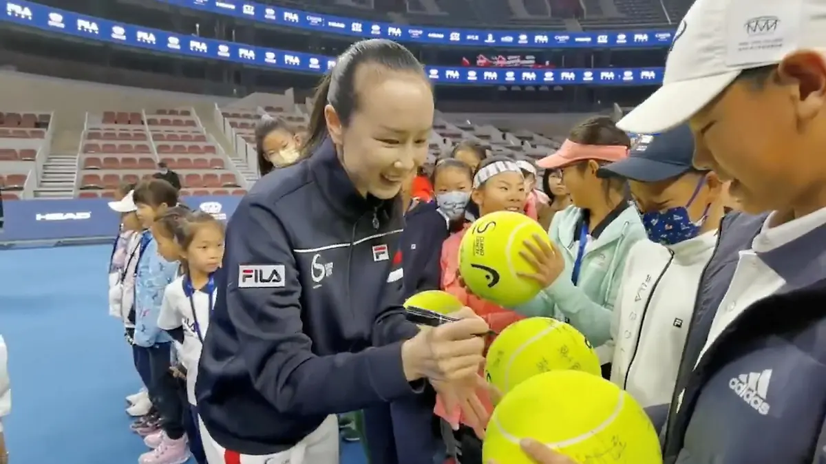 FILE PHOTO: Chinese tennis player Peng Shuai signs large-sized tennis balls at the opening ceremony of Fila Kids Junior Tennis Challenger Final in Beijing, China November 21, 2021, in this screen grab obtained from a social media video. TWITTER @QINGQINGPARIS via REUTERS THIS IMAGE HAS BEEN SUPPLIED BY A THIRD PARTY. MANDATORY CREDIT. NO RESALES. NO ARCHIVES./File Photo
