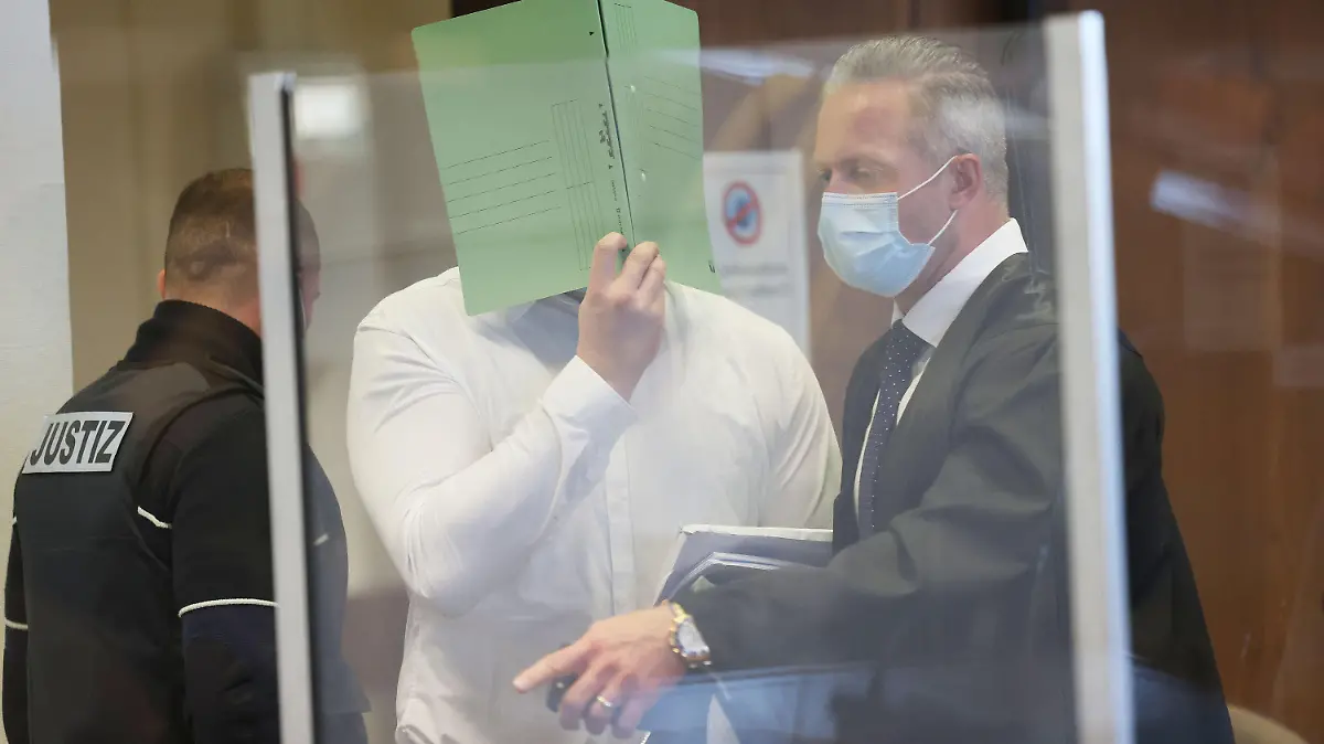 02.12.2021, Nordrhein-Westfalen, Köln: Ein Angeklagter hält sich beim Betreten des Gerichtssaals eine Mappe vor das Gesicht. Eine mutmaßliche Vergewaltigung an Karneval 2020 beschäftigt das Kölner Landgericht. Angeklagt sind drei Männer im Alter zwischen 31 und 42 Jahren. Foto: Oliver Berg/dpa +++ dpa-Bildfunk +++