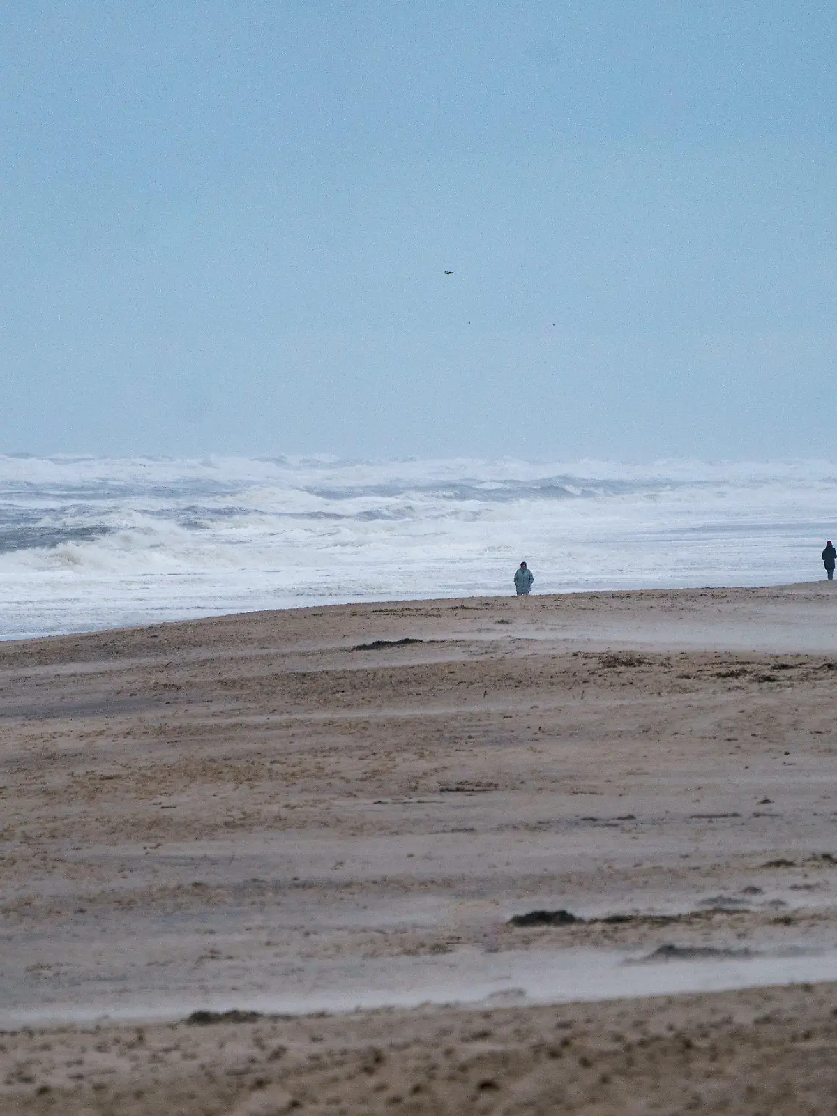 30.11.2021, Schleswig-Holstein, Westerland/Sylt: Spaziergänger gehen am Strand von Westerland entlang, an dem sich durch starke Sturmböen das Wasser zu hohen Wellen auftürmt. Foto: Axel Heimken/dpa +++ dpa-Bildfunk +++