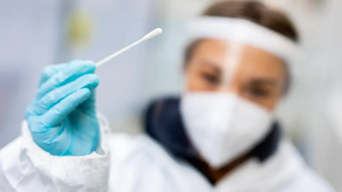 ARCHIV - 13.11.2021, Niedersachsen, Hannover: Die Mitarbeiterin eines Testzentrums in der Innenstadt hält einen Teststab für einen Schnelltest in ihrer Hand. Der Bedarf an Mitarbeitern in niedersächsischen Testzentren ist seit der Verschärfung der Testvorgaben gestiegen. (zu dpa «Deutsches Rotes Kreuz: Personalbedarf in Testzentren hoch») Foto: Moritz Frankenberg/dpa +++ dpa-Bildfunk +++
