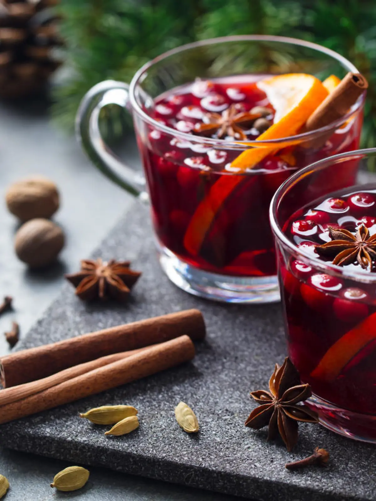 Mulled red wine with spices. Christmas decoration. Grey stone background. Close up.
