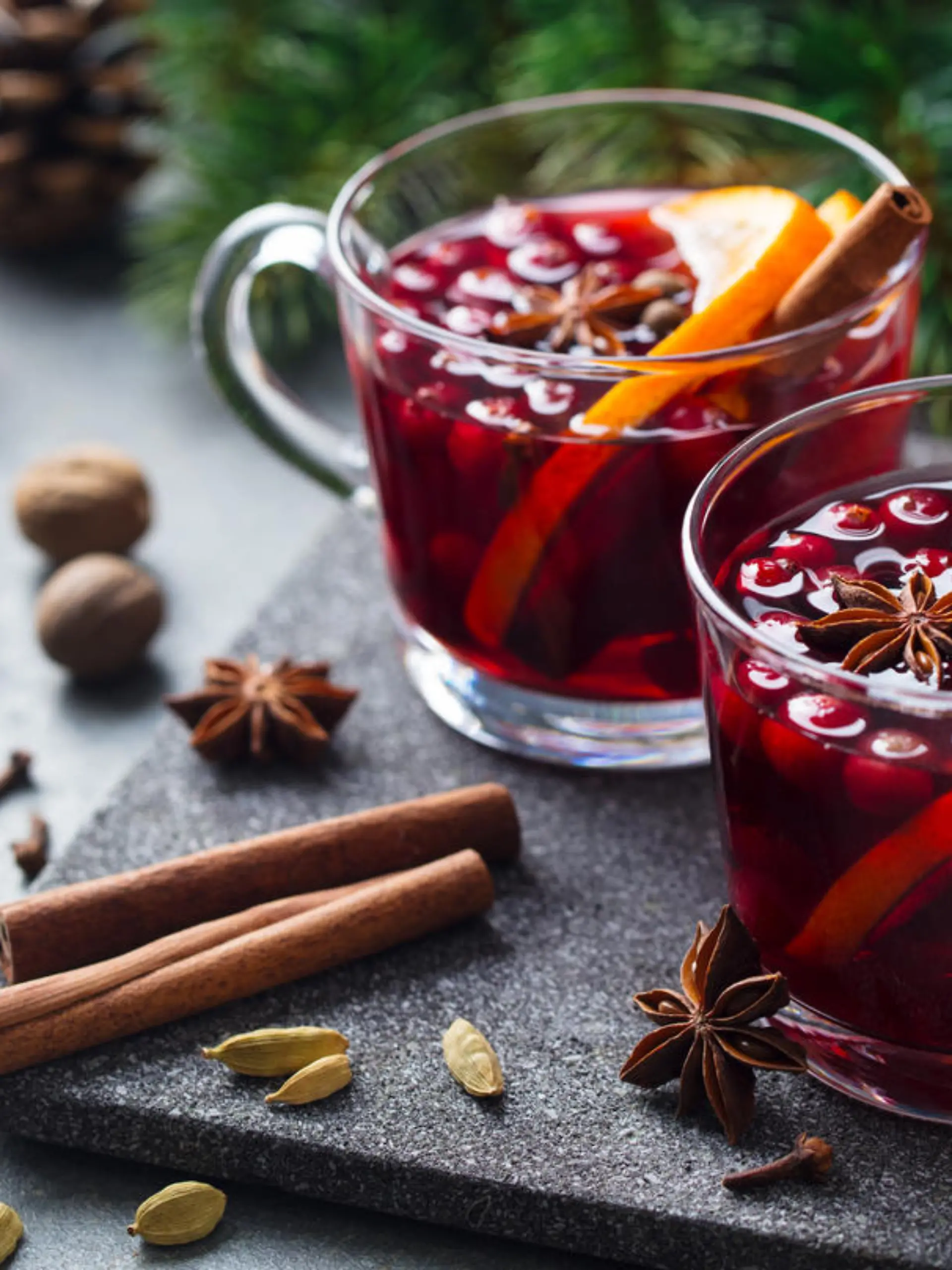 Mulled red wine with spices. Christmas decoration. Grey stone background. Close up.