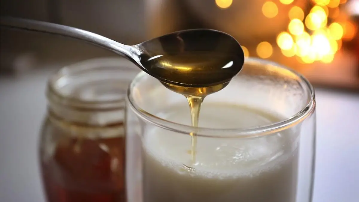 Honig fließt von einem Löffel in ein Glas mit heisser Milch. Jeder kennt irgendein Hausmittel, dass bei Erkältung Abhilfe schafft - angeblich. Denn viel Forschung zu Hausmitteln gibt es nicht. (zu dpa "Erkältungszeit: Hausmittel sind oft eine Wohltat, aber kaum erforscht")