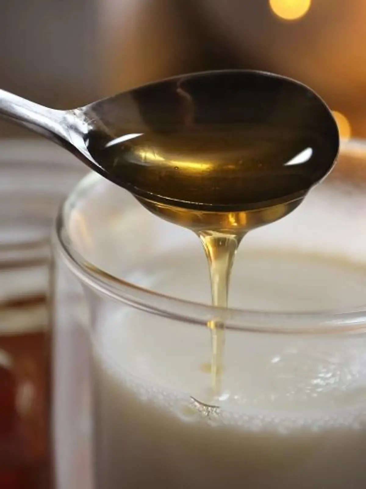 Honig fließt von einem Löffel in ein Glas mit heisser Milch. Jeder kennt irgendein Hausmittel, dass bei Erkältung Abhilfe schafft - angeblich. Denn viel Forschung zu Hausmitteln gibt es nicht. (zu dpa "Erkältungszeit: Hausmittel sind oft eine Wohltat, aber kaum erforscht")