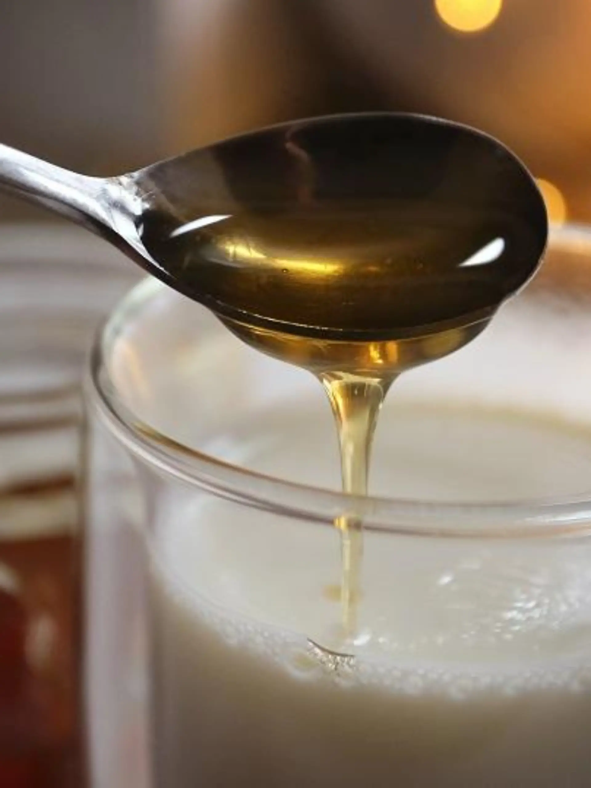 Honig fließt von einem Löffel in ein Glas mit heisser Milch. Jeder kennt irgendein Hausmittel, dass bei Erkältung Abhilfe schafft - angeblich. Denn viel Forschung zu Hausmitteln gibt es nicht. (zu dpa "Erkältungszeit: Hausmittel sind oft eine Wohltat, aber kaum erforscht")