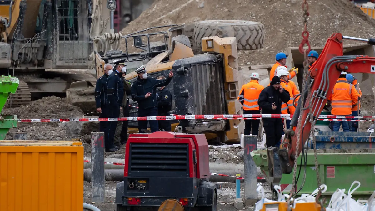 01.12.2021, Bayern, München: Polizisten und Bahnbedienstete stehen auf einer Baustelle auf einem Bahngelände an der Donnersbergerbrücke neben einem umgestürzten Radlader. Bei der Explosion einer Fliegerbombe aus dem Zweiten Weltkrieg sind an der Bahnstrecke zum Hauptbahnhof in München mehrere Menschen verletzt worden. Der gesamte Zugverkehr zum und vom Hauptbahnhof wurde stundenlang eingestellt. Foto: Sven Hoppe/dpa +++ dpa-Bildfunk +++