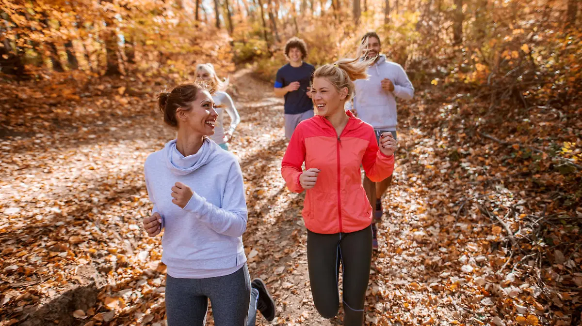 Organized small group of people running in woods in autumn.