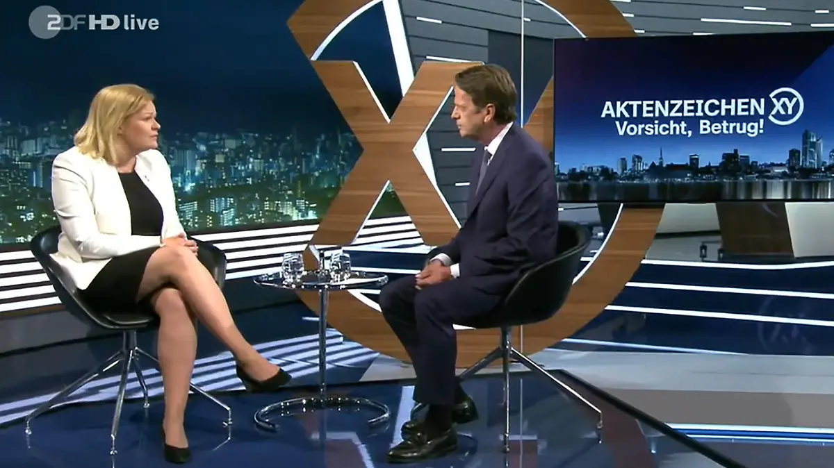 31.05.2023, Bayern, München: Bundesinnenministerin Nancy Faeser (SPD) unterhält sich mit Moderator Rudi Cerne in der TV-Sendung «Aktenzeichen XY». Die TV-Sendung «Aktenzeichen XY» legt an diesem Mittwoch einen Schwerpunkt auf aktuelle Betrugsmaschen, mit denen gutgläubige Opfer oftmals um ihr gesamtes Vermögen gebracht werden. Foto: --/Securetel/ZDF /dpa +++ dpa-Bildfunk +++
