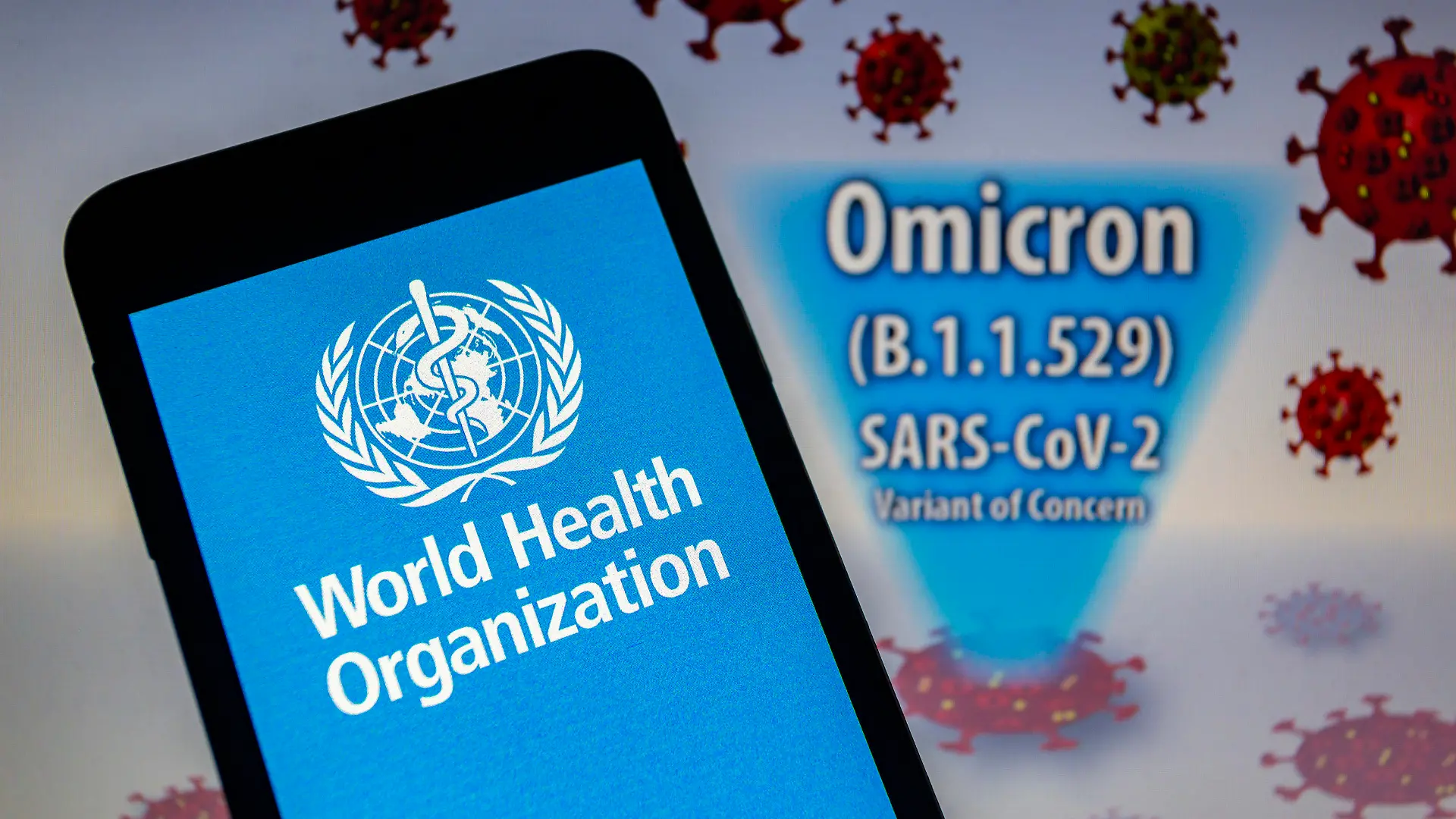 28.11.2021, Paraguay, Asunción: ILLUSTRATION - Logo der Weltgesundheitsorganisation (WHO) auf einem Smartphone vor einer visuellen Darstellung der neu entdeckten Virusvariante Omikron. Am 26. November 2021 hat die WHO die SARS-CoV-2-Variante B.1.1.529 auf Anraten der Technischen Beratungsgruppe für Virusevolution (TAG-VE) der WHO als besorgniserregende Variante mit der Bezeichnung Omicron eingestuft. Die Ausbreitung der zunächst im Süden Afrikas entdeckten Omikron-Variante des Coronavirus sorgt weltweit für Beunruhigung. Foto: Andre M. Chang/ZUMA Press Wire/dpa +++ dpa-Bildfunk +++