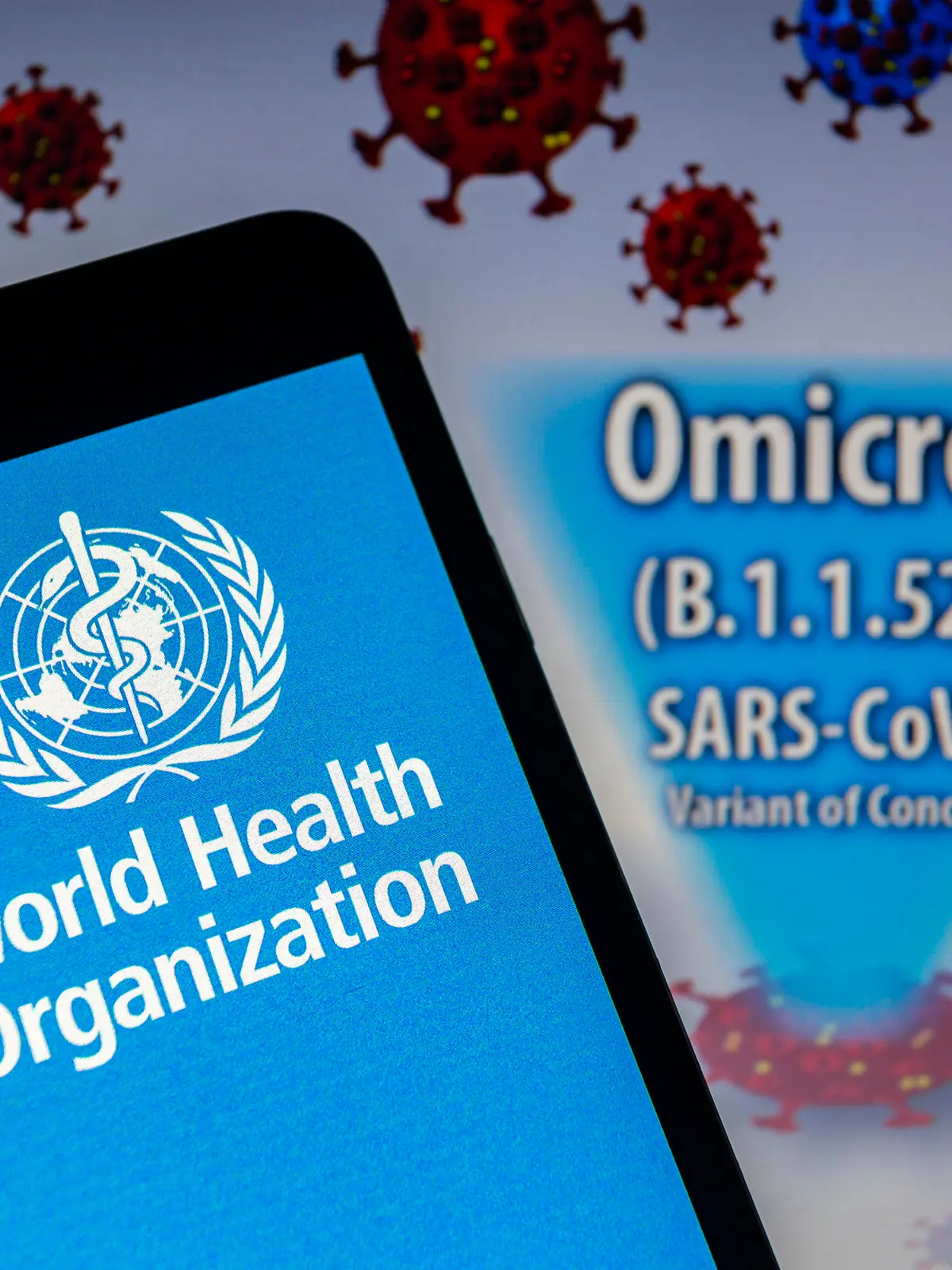 28.11.2021, Paraguay, Asunción: ILLUSTRATION - Logo der Weltgesundheitsorganisation (WHO) auf einem Smartphone vor einer visuellen Darstellung der neu entdeckten Virusvariante Omikron. Am 26. November 2021 hat die WHO die SARS-CoV-2-Variante B.1.1.529 auf Anraten der Technischen Beratungsgruppe für Virusevolution (TAG-VE) der WHO als besorgniserregende Variante mit der Bezeichnung Omicron eingestuft. Die Ausbreitung der zunächst im Süden Afrikas entdeckten Omikron-Variante des Coronavirus sorgt weltweit für Beunruhigung. Foto: Andre M. Chang/ZUMA Press Wire/dpa +++ dpa-Bildfunk +++