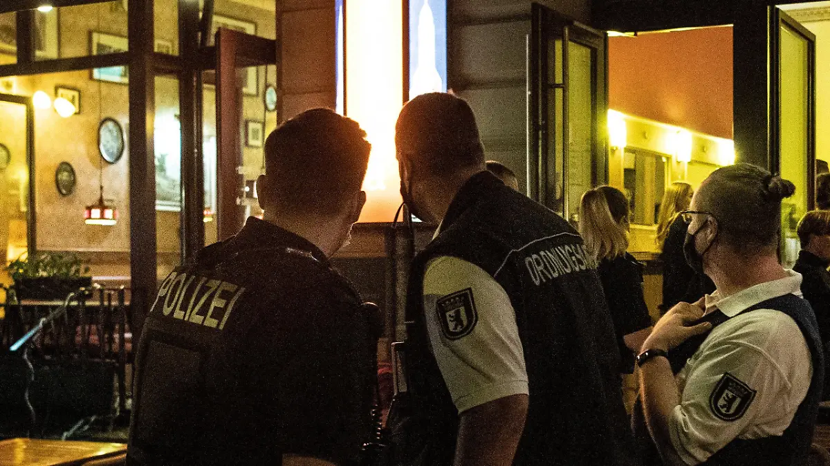 ARCHIV - 24.07.2020, Berlin: Ein Polizeibeamter und zwei Mitarbeiter des Ordnungsamtes stehen vor einem Lokal. Angesichts der verschärften Corona-Regeln hält die Gewerkschaft der Polizei (GdP) eine Impfpflicht für Polizisten erforderlich. (zu dpa «Berliner Gewerkschaft will Impfpflicht für Polizei») Foto: Paul Zinken/dpa +++ dpa-Bildfunk +++