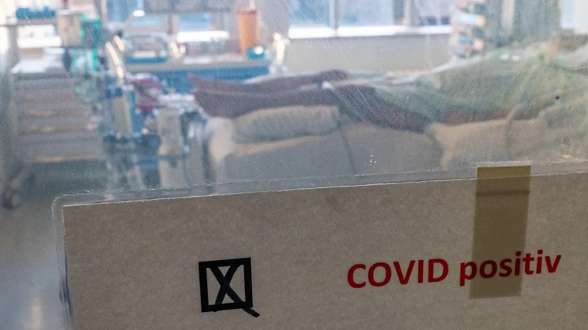 22.11.2021, Sachsen-Anhalt, Halle (Saale): Ein schwer an Covid-19 erkrankter Patient liegt hinter einem Schild mit dem Hinweis ·Covid positiv· in einem Isolierzimmer auf der Corona-Intensivstation im Universitätsklinikum in Halle/Saale. Das Krankenhaus ist ein Zentrum der Behandlung von Covid-19-Patienten in der Region. (Zu dpa "«Es ist grausam» - Schwerstarbeit auf Corona-Intensivstation") Foto: Hendrik Schmidt/dpa-Zentralbild/dpa +++ dpa-Bildfunk +++