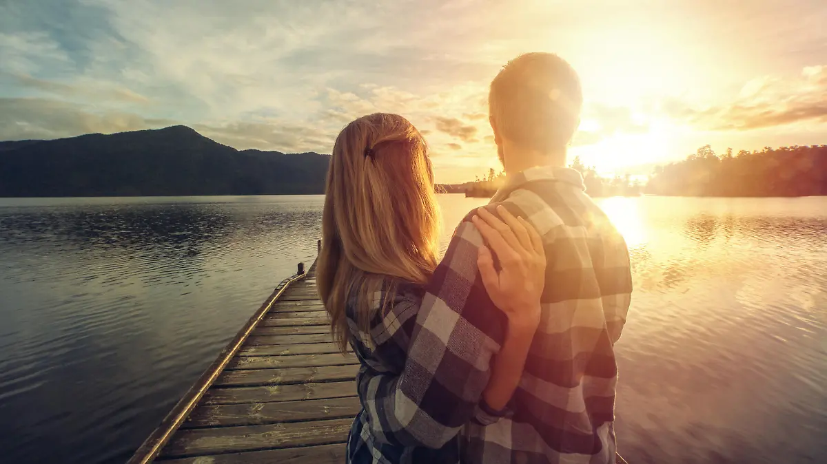 Cheerful young couple on a lake pier being affectionate. Lake Kaniere, New Zealand.