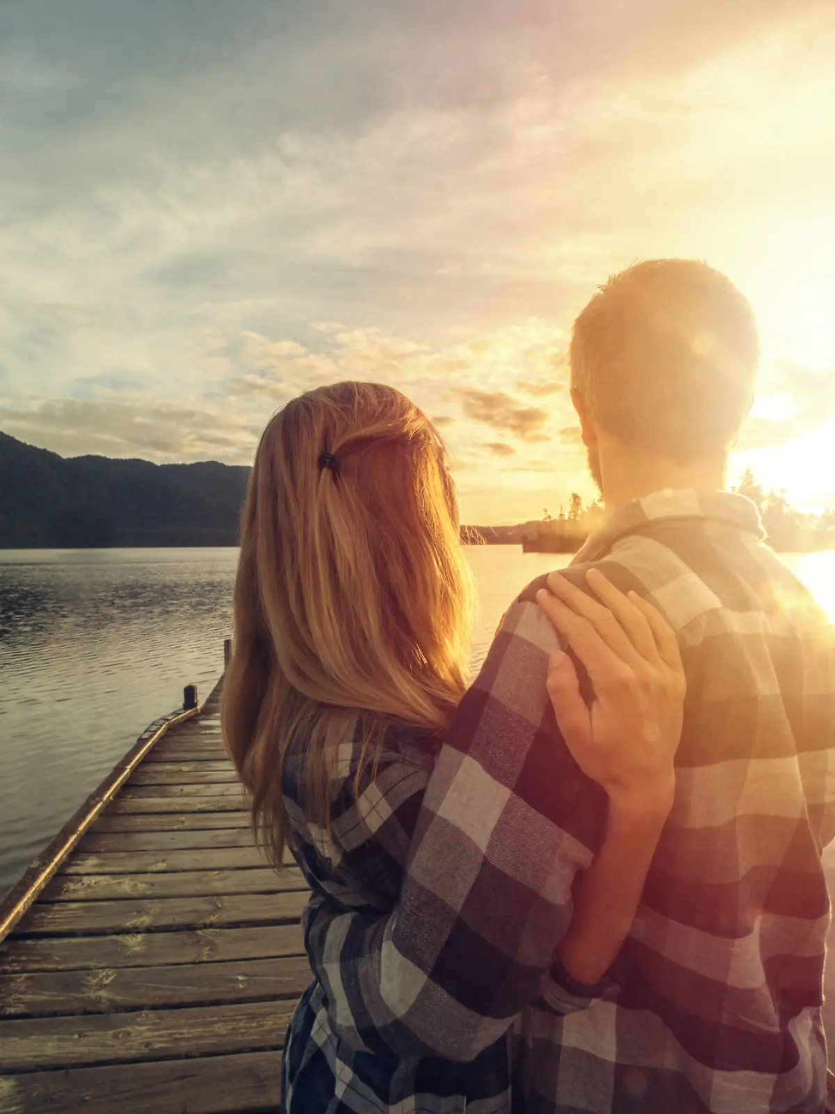 Cheerful young couple on a lake pier being affectionate. Lake Kaniere, New Zealand.