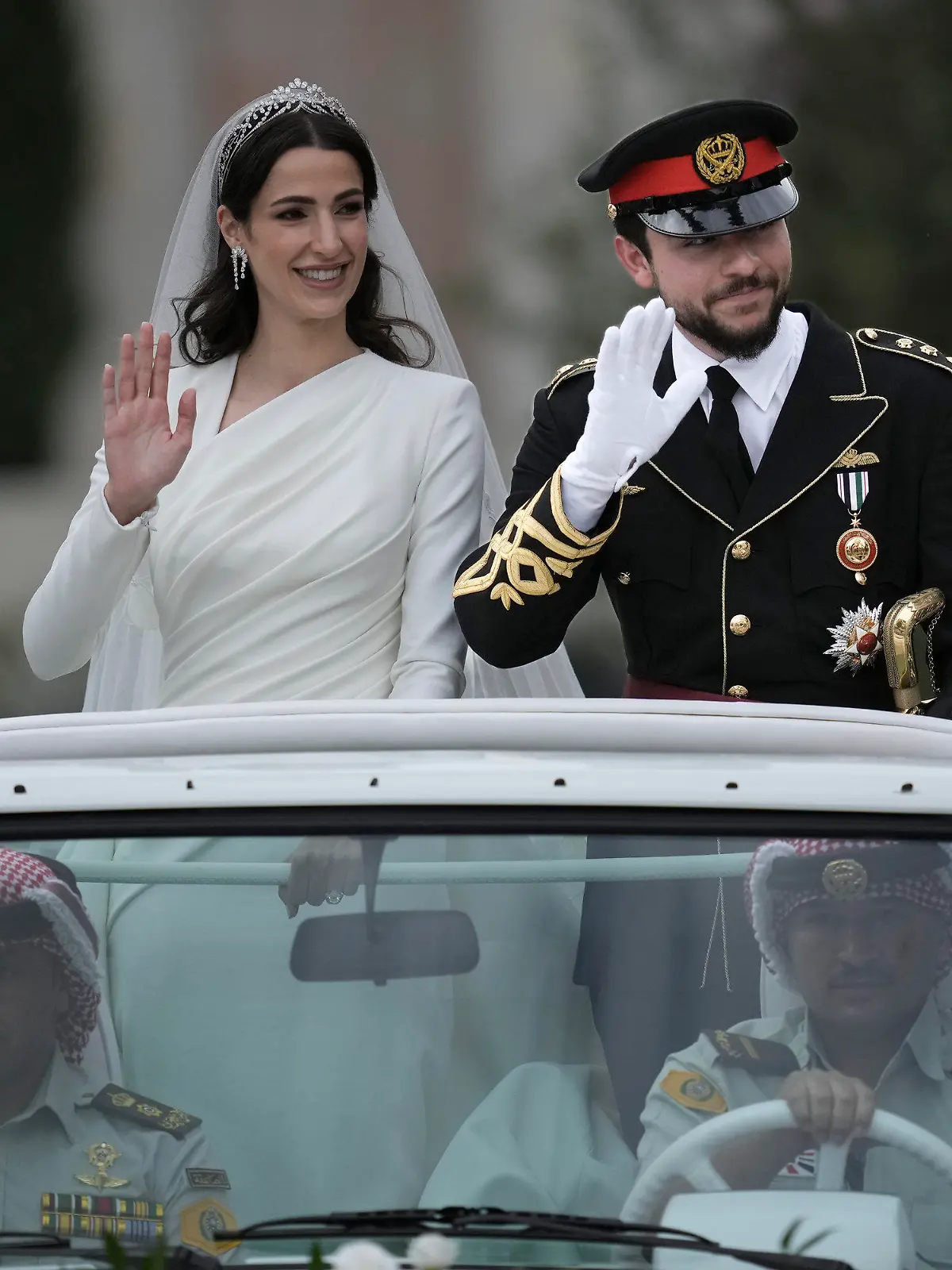 01.06.2023, Jordanien, Amman: Die saudische Architektin Rajwa Alsaif (l) und der jordanische Kronprinz Hussein bin Abdullah II fahren anlässlich ihrer Hochzeit in einem offenen Wagen durch Amman. Foto: Nasser Nasser/AP +++ dpa-Bildfunk +++