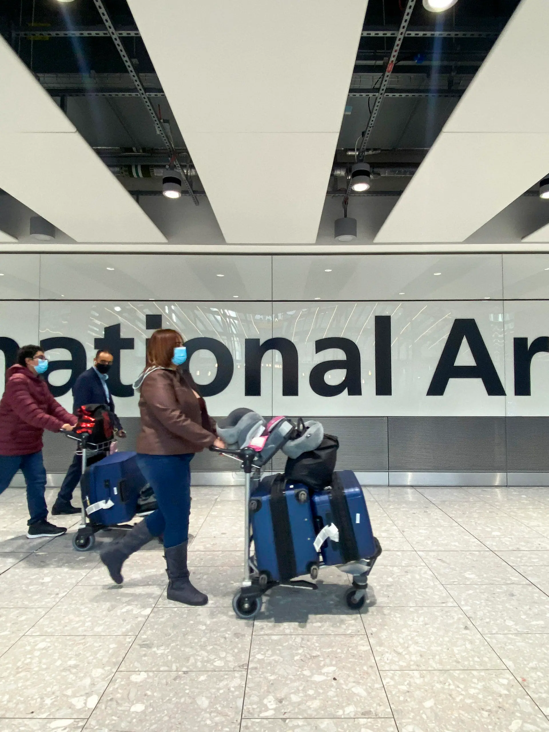 26.11.2021, Großbritannien, London Heathrow: Passagiere gehen mit ihrem Gepäck durch das Ankunftsterminal auf dem Londoner Flughafen Heathrow. Nach der Entdeckung einer neuen Virusvariante gab die Regierung von Großbritannien bekannt, dass es ein Flugverbot für Flüge aus Südafrika und fünf anderen Ländern des südlichen Afrikas verhängt hat und dass alle Personen einen Corona-Test durchführen müssen, die kürzlich aus diesen Ländern eingereist sind. Foto: Alberto Pezzali/AP/dpa +++ dpa-Bildfunk +++