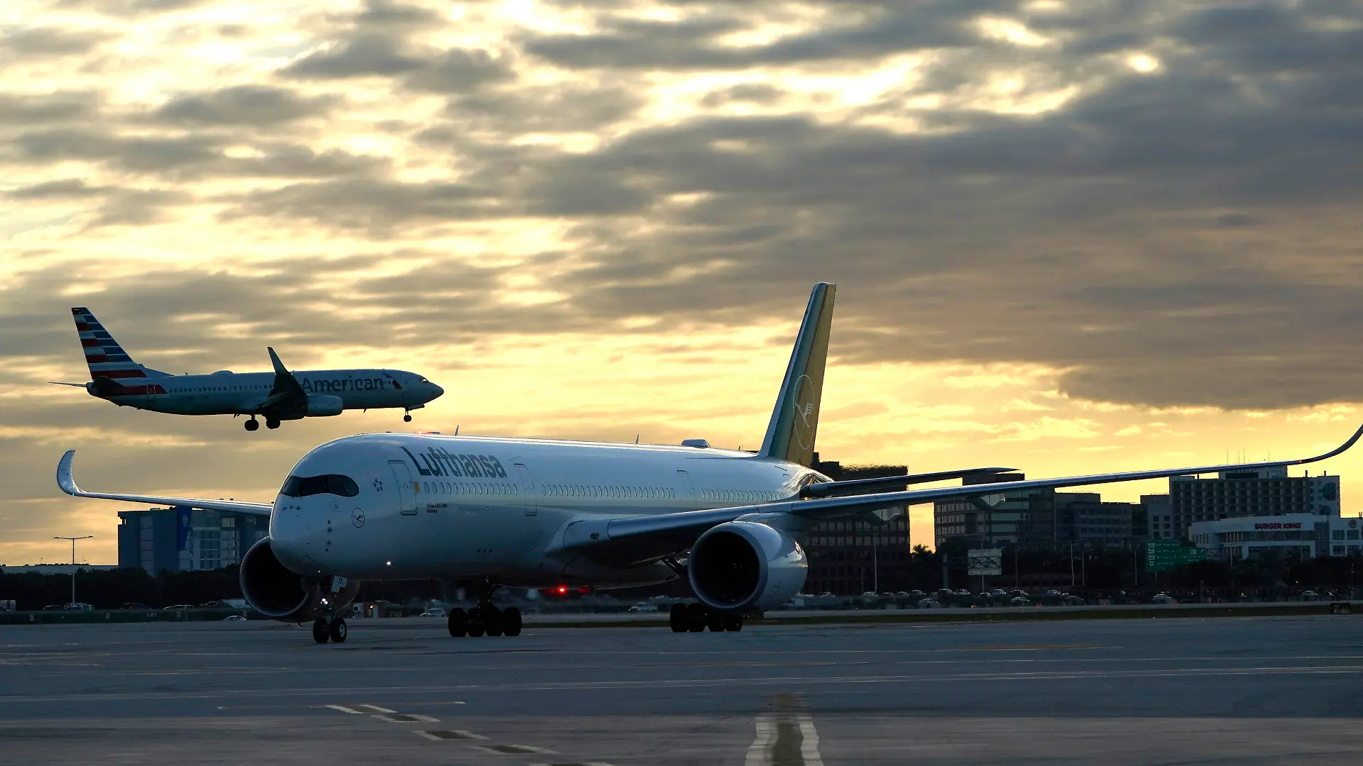 08.11.2021, USA, Miami: Ein Lufthansa-Flug kommt aus München, Deutschland, an, während ein Flugzeug der American Airlines zur Landung auf dem Miami International Airport in Miami ansetzt. Mehr als anderthalb Jahre, nachdem die USA aufgrund von COVID-19-Bedenken ihre Grenzen für internationale Reisende aus Ländern wie Brasilien, China, Indien, Südafrika, dem Vereinigten Königreich und weiten Teilen Europas geschlossen haben, verschieben sich die Beschränkungen und konzentrieren sich auf den Impfstatus. Ab Montag sind die Reiseverbote für bestimmte Länder aufgehoben. Die USA werden internationale Reisende einreisen lassen, aber sie müssen geimpft sein - mit einigen Ausnahmen. Foto: Lynne Sladky/AP/dpa +++ dpa-Bildfunk +++