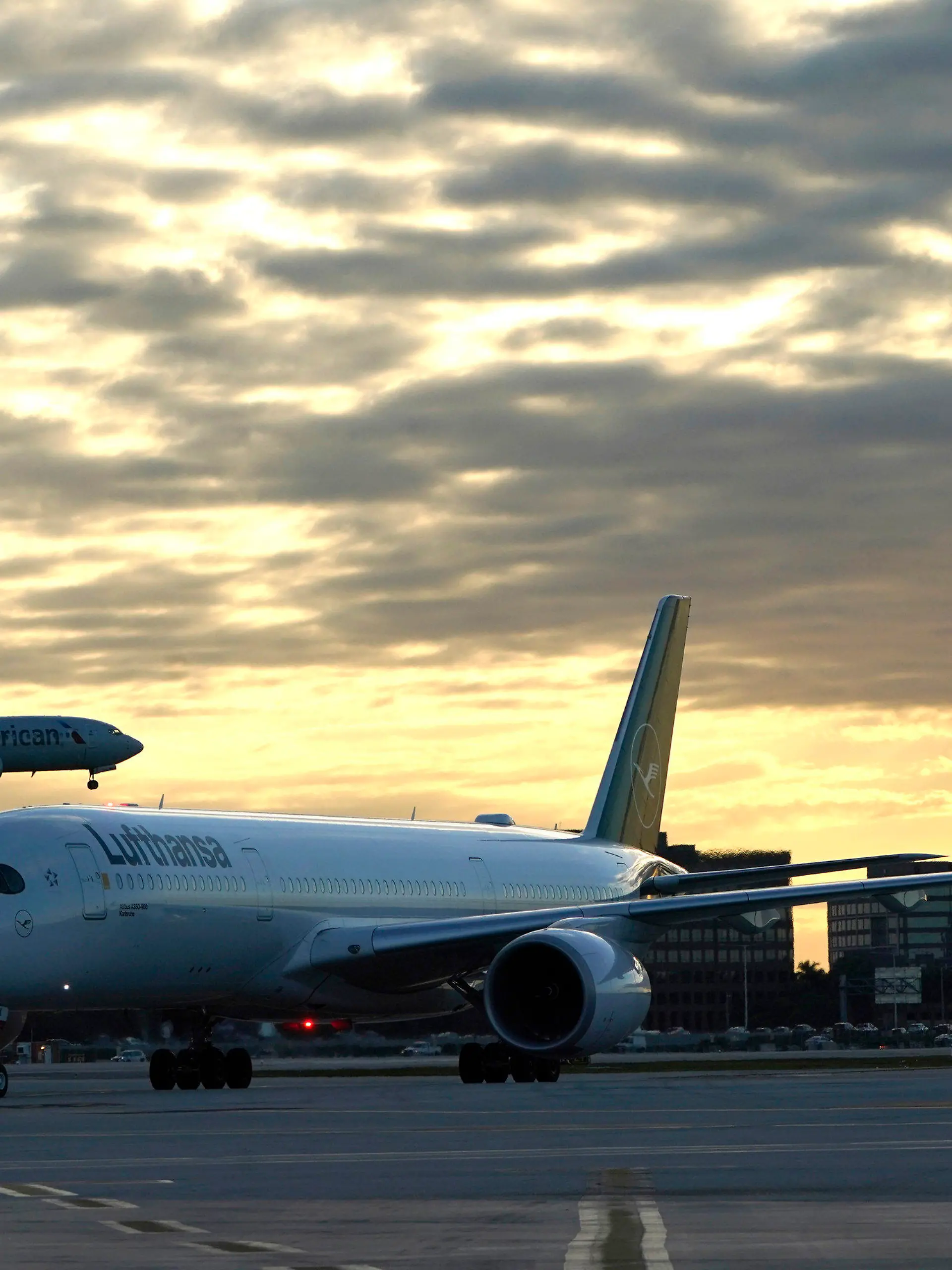 08.11.2021, USA, Miami: Ein Lufthansa-Flug kommt aus München, Deutschland, an, während ein Flugzeug der American Airlines zur Landung auf dem Miami International Airport in Miami ansetzt. Mehr als anderthalb Jahre, nachdem die USA aufgrund von COVID-19-Bedenken ihre Grenzen für internationale Reisende aus Ländern wie Brasilien, China, Indien, Südafrika, dem Vereinigten Königreich und weiten Teilen Europas geschlossen haben, verschieben sich die Beschränkungen und konzentrieren sich auf den Impfstatus. Ab Montag sind die Reiseverbote für bestimmte Länder aufgehoben. Die USA werden internationale Reisende einreisen lassen, aber sie müssen geimpft sein - mit einigen Ausnahmen. Foto: Lynne Sladky/AP/dpa +++ dpa-Bildfunk +++