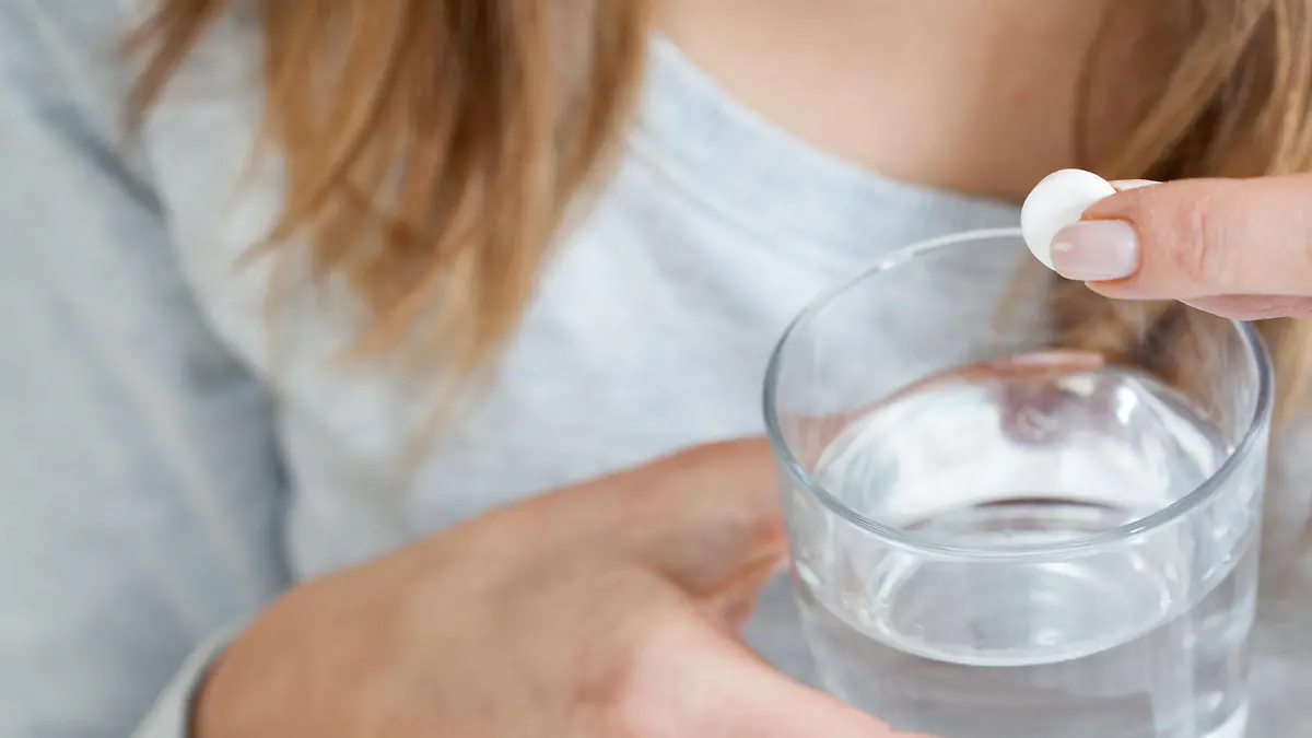 Horizontal view of ill woman taking aspirin
