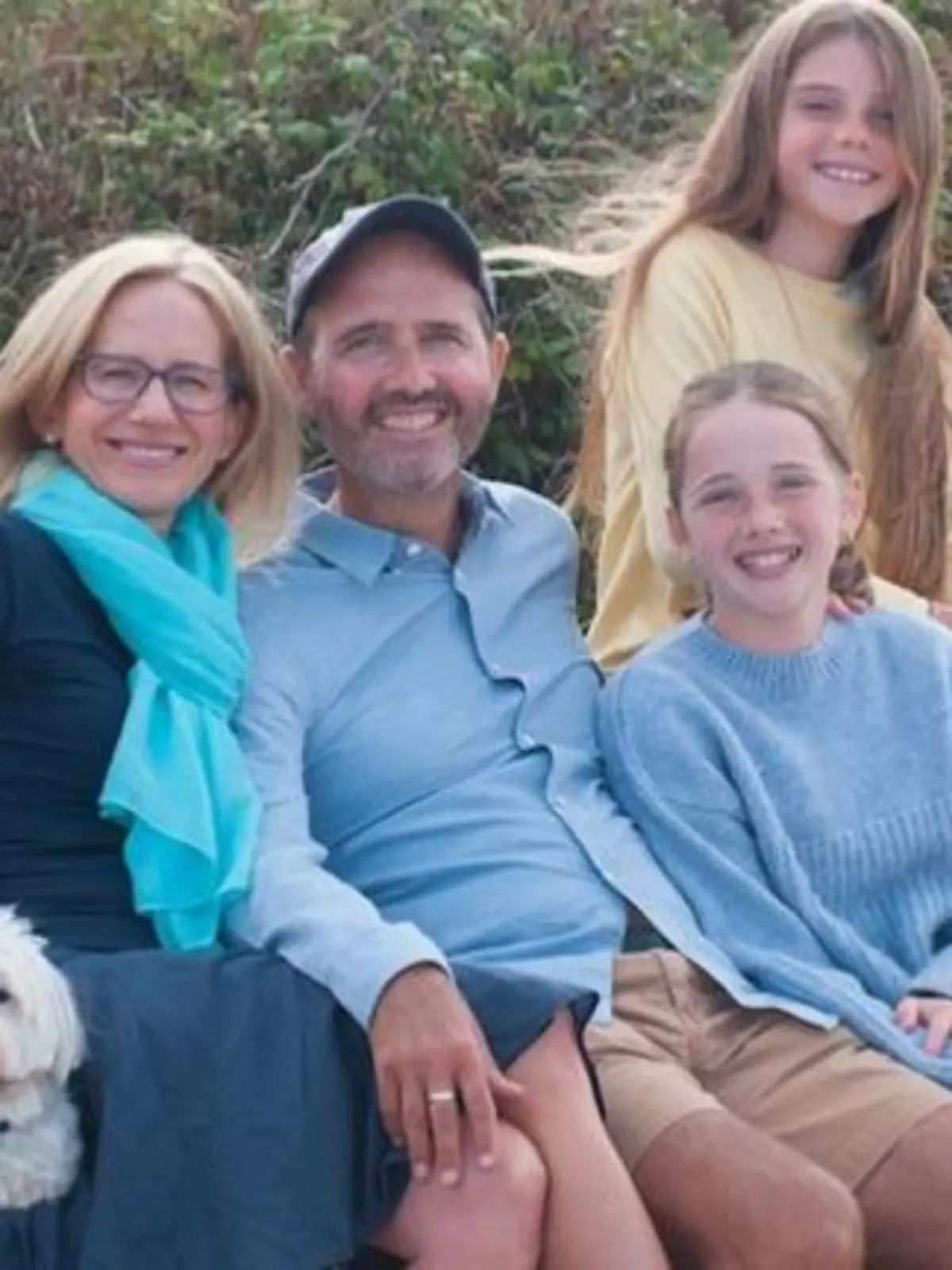Eine vierköpfige Familie posiert zusammen und lächelt in die Kamera.