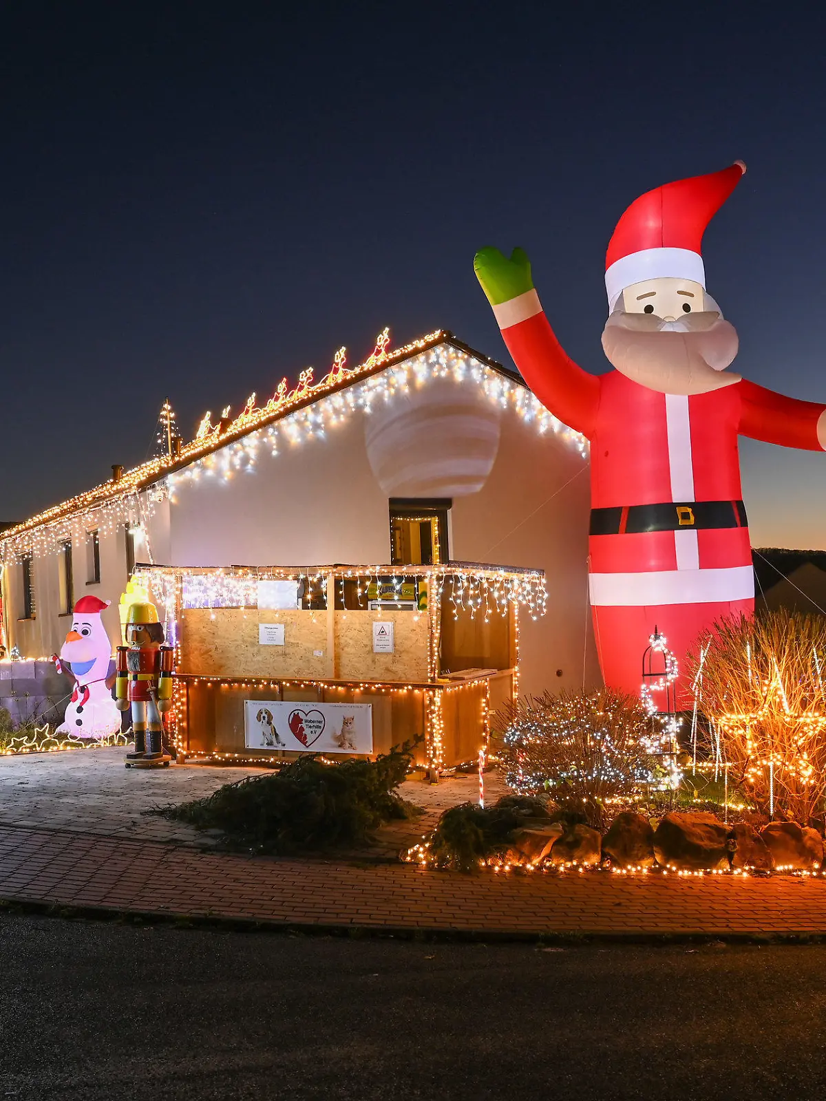 22.11.2021, Hessen, Ahnatal: Zur blauen Stunde wird das Weihnachtshaus das erste Mal in dieser Saison in voller Beleuchtung gezeigt. Dominik Pieczko und Sascha Bärwald haben für die prachtvolle Weihnachts-Illumination rund 65 000 LEDs verwendet. Foto: Uwe Zucchi/dpa +++ dpa-Bildfunk +++