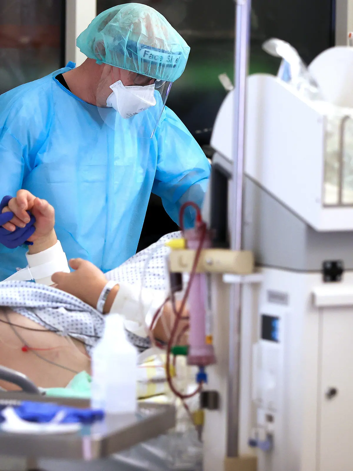 dpatopbilder - ARCHIV - 15.11.2021, Sachsen, Leipzig: Ein Facharzt versorgt einen Covid-19-Patienten auf der Intensivstation der Leipziger Uniklinik und hält dessen Hand. (zu dpa "Intensivmediziner: Corona-Lage sehr besorgniserregend") Foto: Jan Woitas/dpa-Zentralbild/dpa +++ dpa-Bildfunk +++