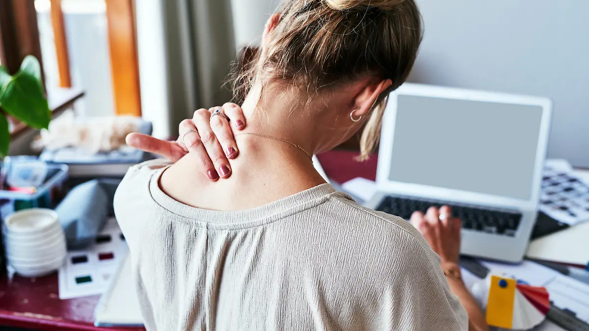 Rearview shot of a designer experiencing discomfort in her shoulders while sitting at her desk