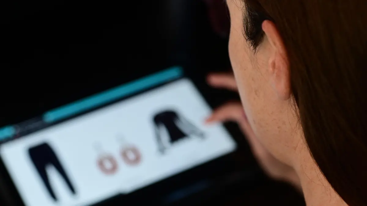 Over the shoulder selective focuse view of an young adult woman shopping fashion clothing online using a tablet., Credit:Avalon / Avalon