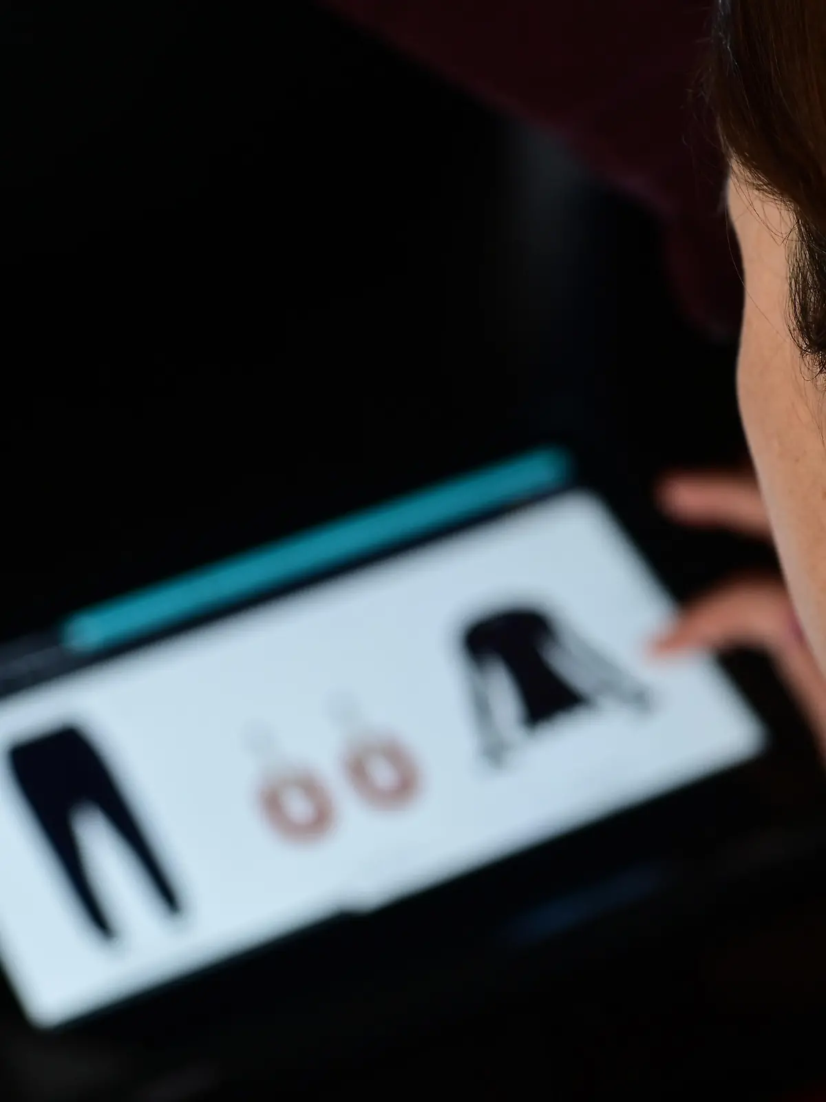 Over the shoulder selective focuse view of an young adult woman shopping fashion clothing online using a tablet., Credit:Avalon / Avalon
