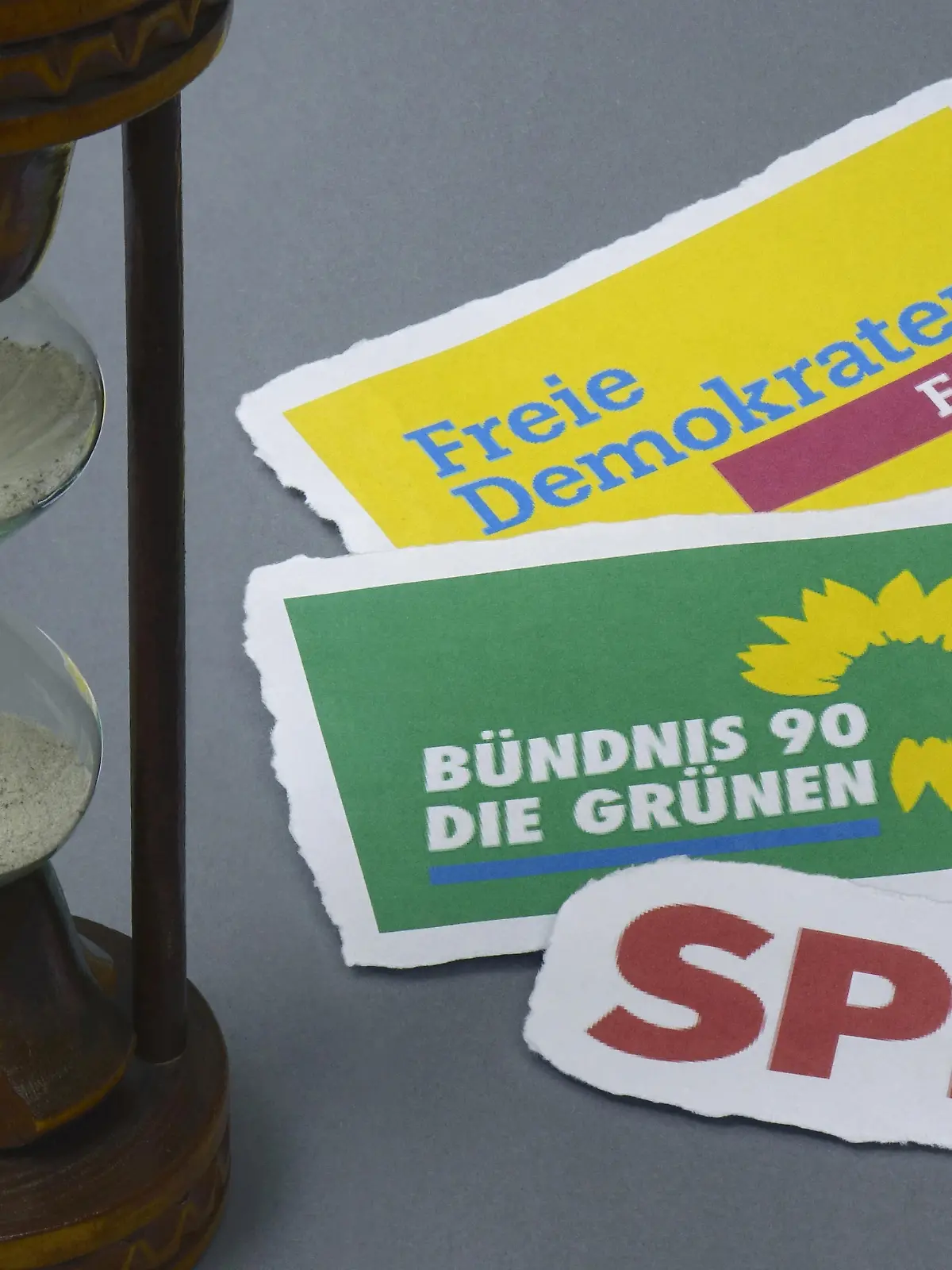 25.10.2021, Borkwalde, Brandenburg, Auf einem grauen Untergrund liegen Parteilogos und steht eine Sanduhr.