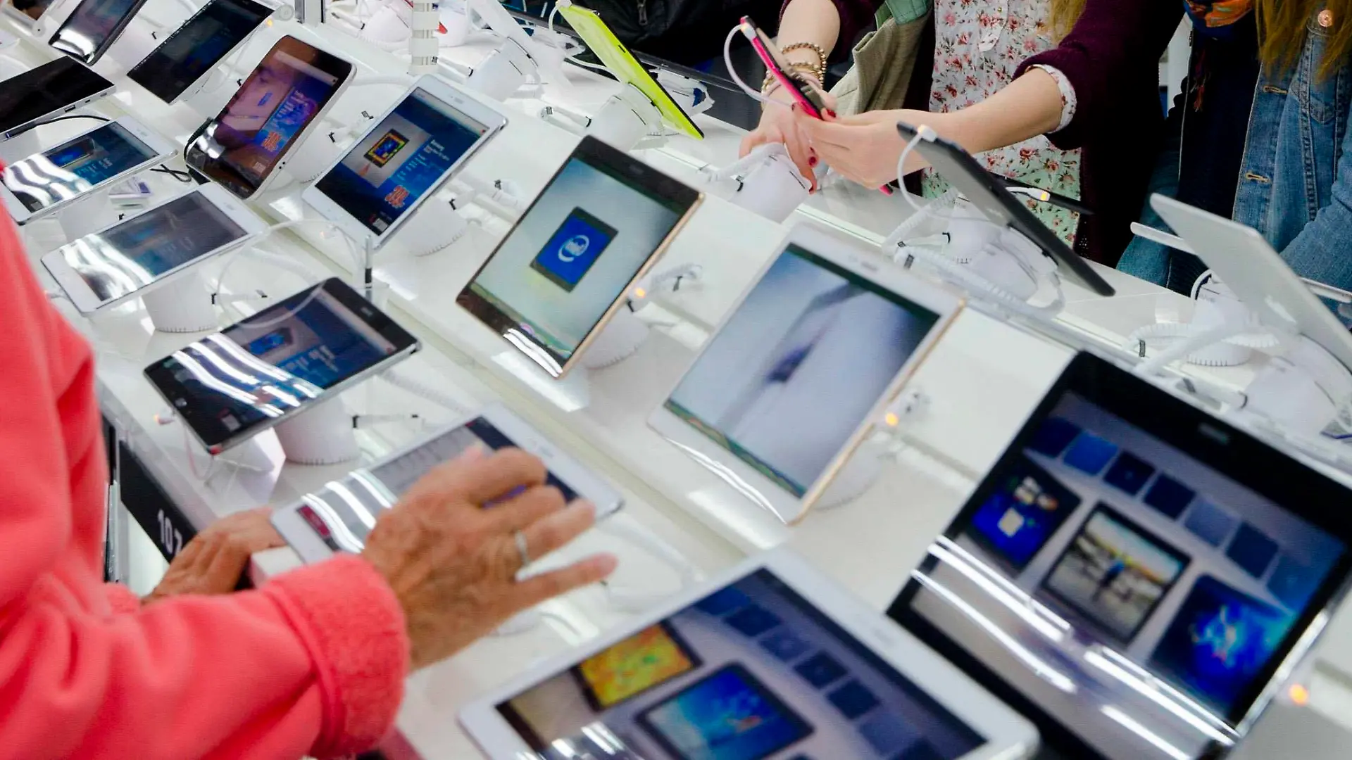 People look at tablet computers at the Saturn electronic retailer in the newly opened Mall of Berlin shopping centre in Berlin September 25, 2014. The gigantic German department store, rebuilt in the heart of Berlin on the rubble of a shopping center seized by the Nazis, was opened on Thursday with a ceremony paying tribute to its original Jewish owners. The near 1 billion euro ($1.3 billion) "Mall of Berlin" - an entire quarter with a glass-covered arcade, 270 shops, a hotel and flats - marks the spot where the Wertheim store was built in 1896. Picture taken September 25.  REUTERS/Thomas Peter (GERMANY - Tags: BUSINESS SOCIETY TELECOMS)