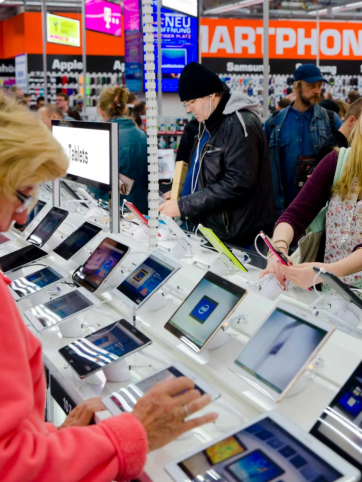 People look at tablet computers at the Saturn electronic retailer in the newly opened Mall of Berlin shopping centre in Berlin September 25, 2014. The gigantic German department store, rebuilt in the heart of Berlin on the rubble of a shopping center seized by the Nazis, was opened on Thursday with a ceremony paying tribute to its original Jewish owners. The near 1 billion euro ($1.3 billion) "Mall of Berlin" - an entire quarter with a glass-covered arcade, 270 shops, a hotel and flats - marks the spot where the Wertheim store was built in 1896. Picture taken September 25.  REUTERS/Thomas Peter (GERMANY - Tags: BUSINESS SOCIETY TELECOMS)